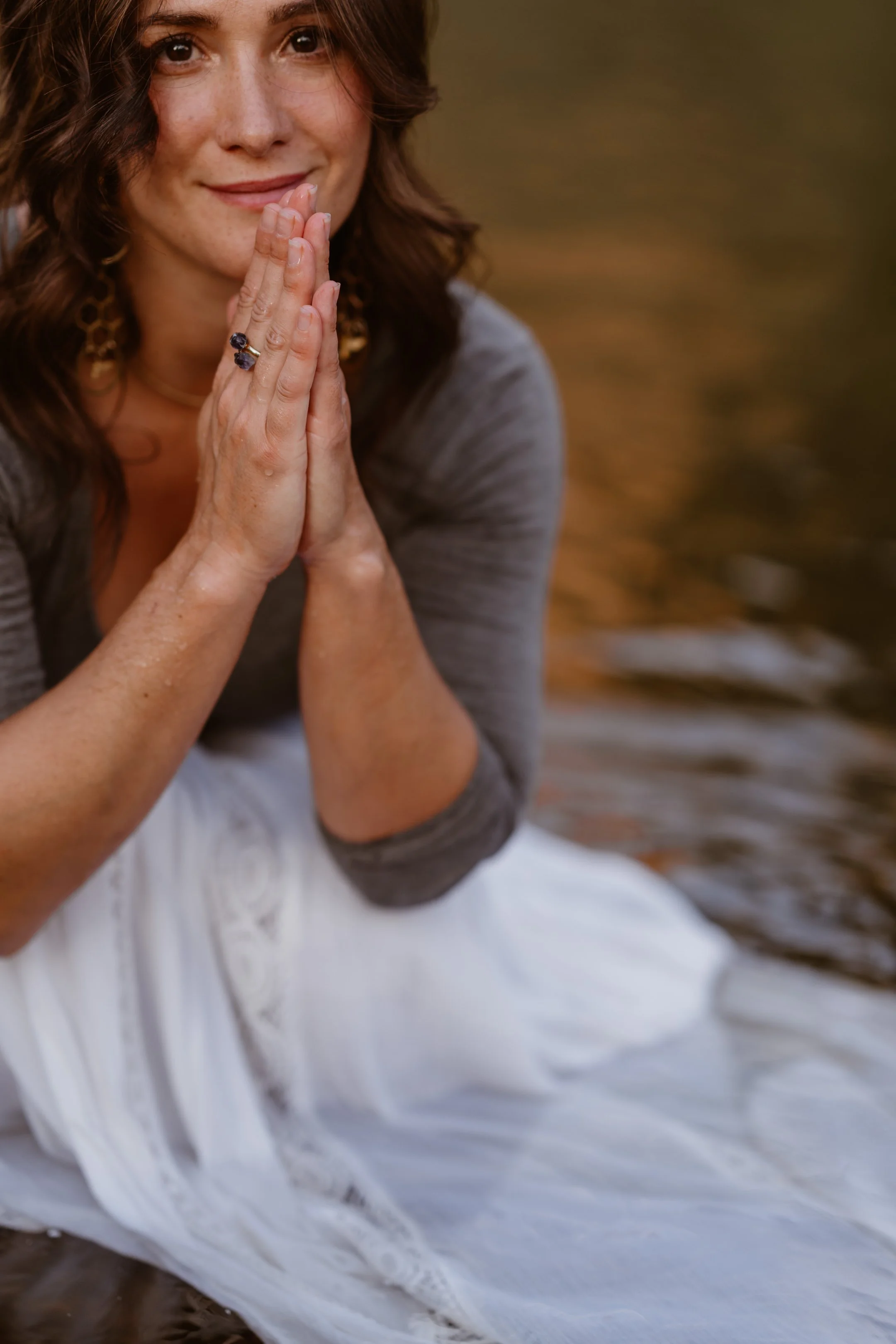 Dori Lewis crouches in a river with her hands in prayer position near her face.