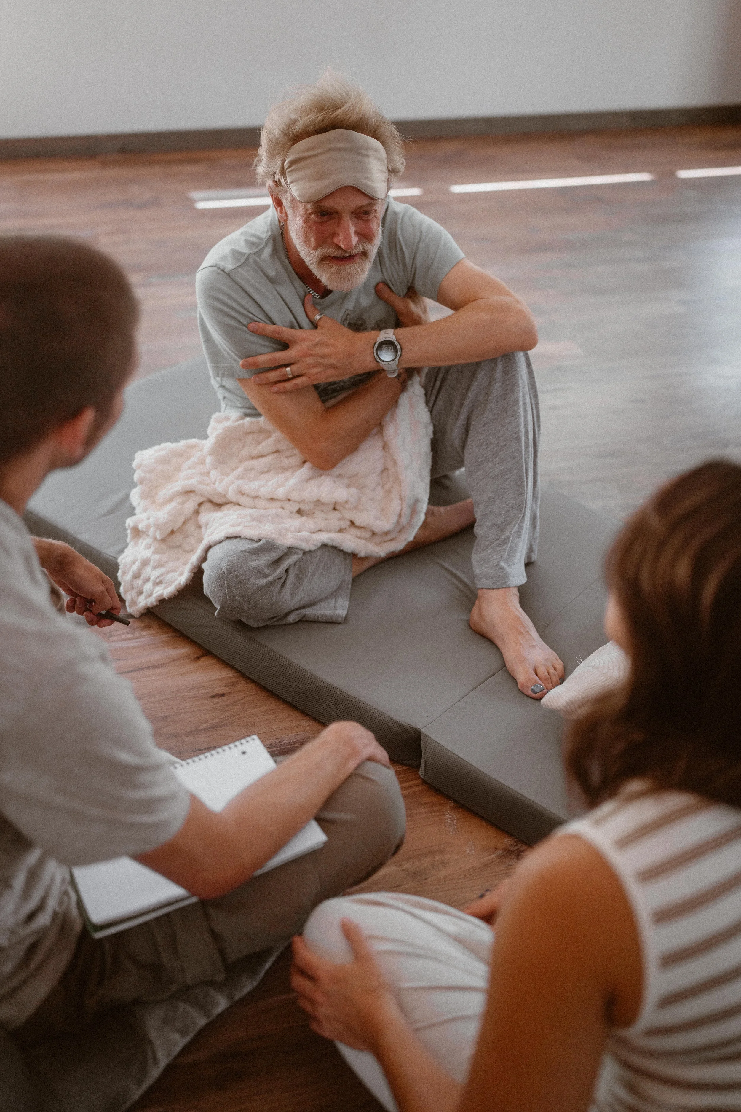 Psilocybin therapy patient talks to clinicians while seated on a comfortable cushion.