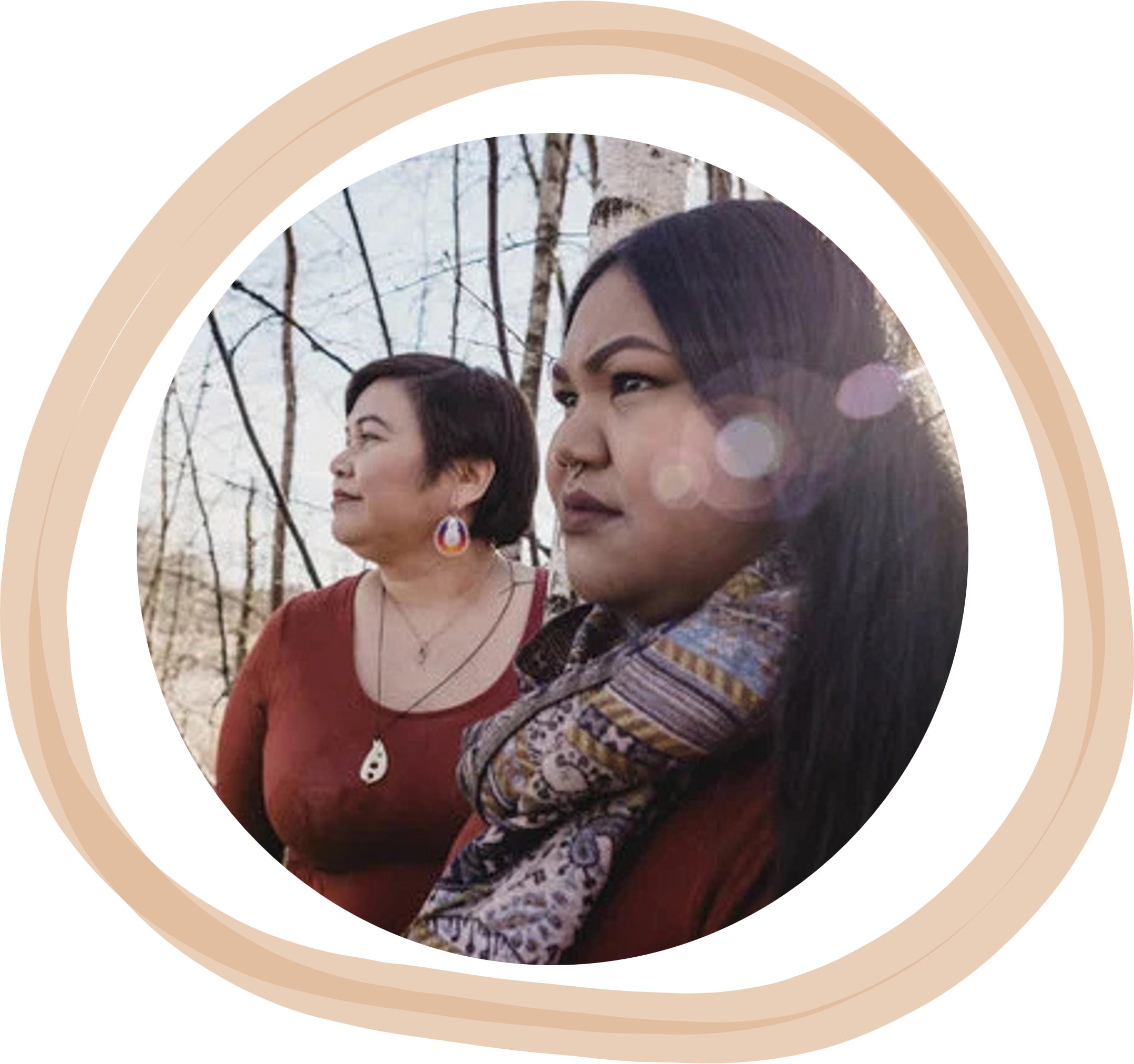 Two women standing outdoors, looking to the left, near leafless trees with snow in the background.
