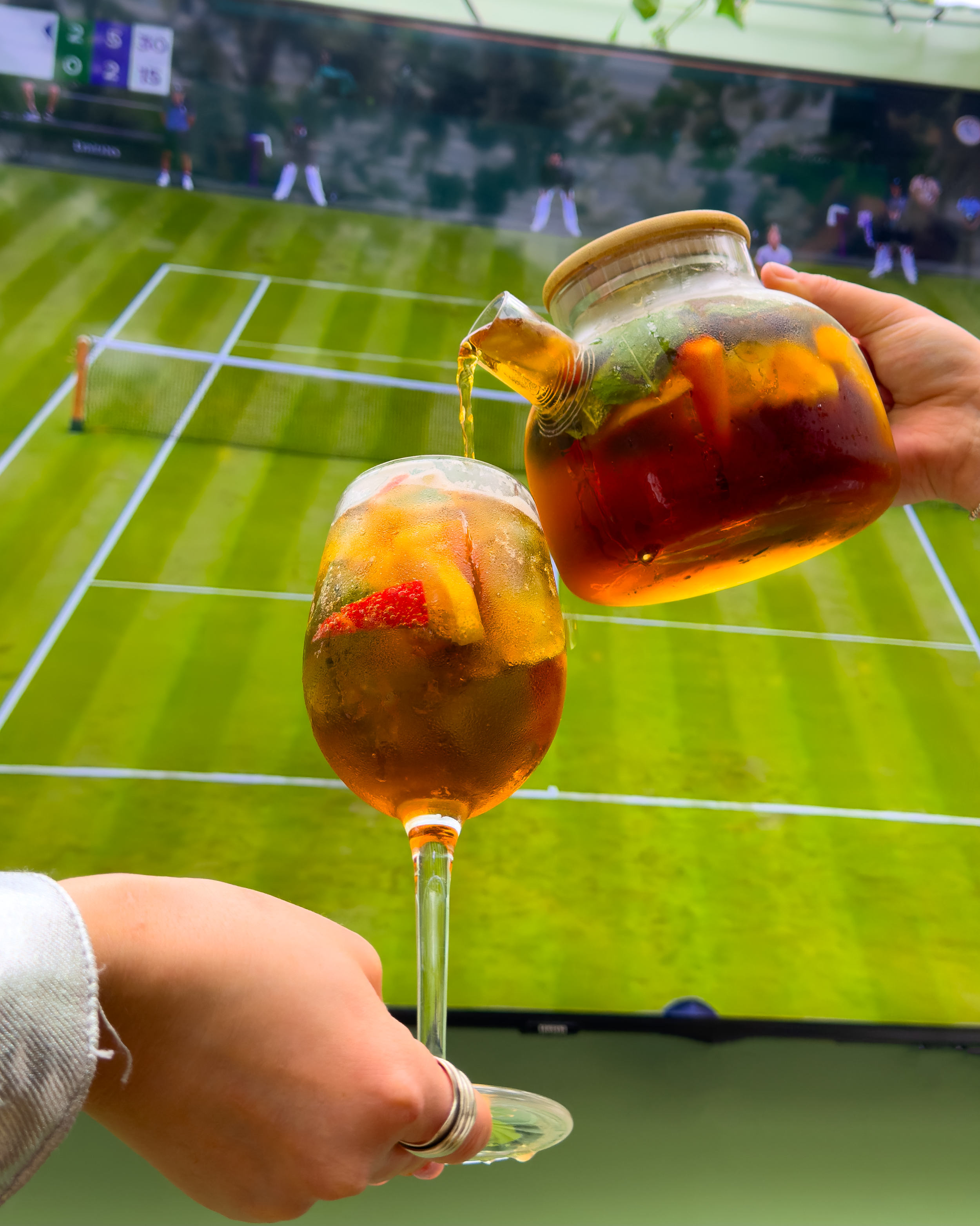 Pouring a cocktail infront of a screen showing tennis