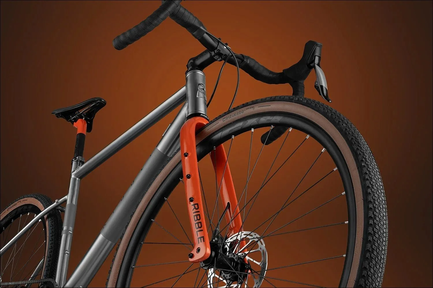 Grey and orange gravel bike product photograph against a warm orange backdrop