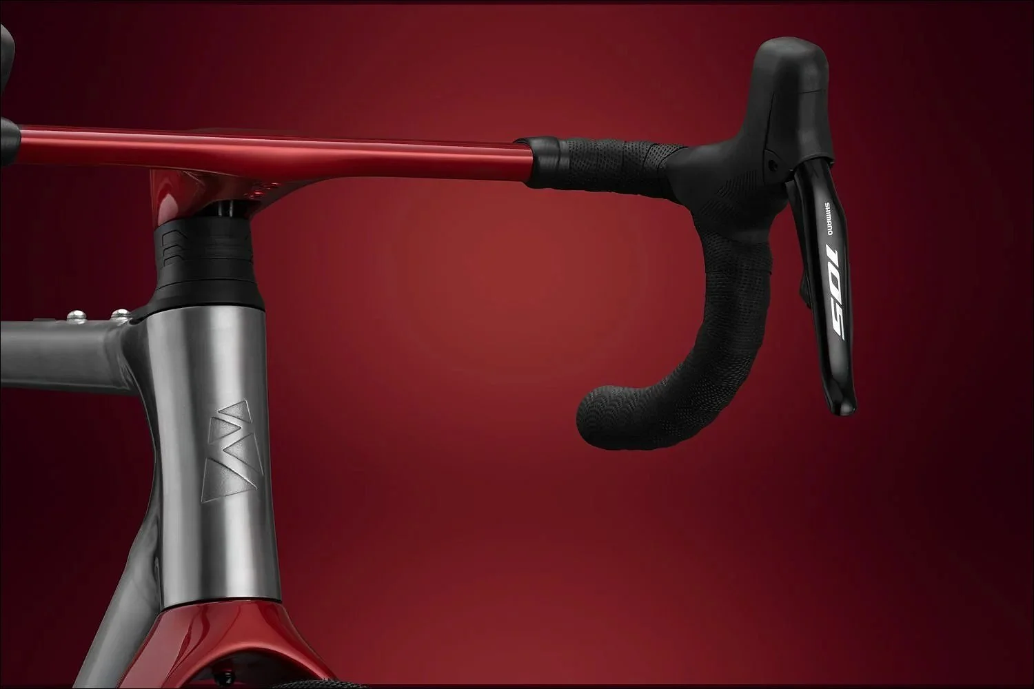 Close-up of a red drop handlebar and silver stem against a dark red background.