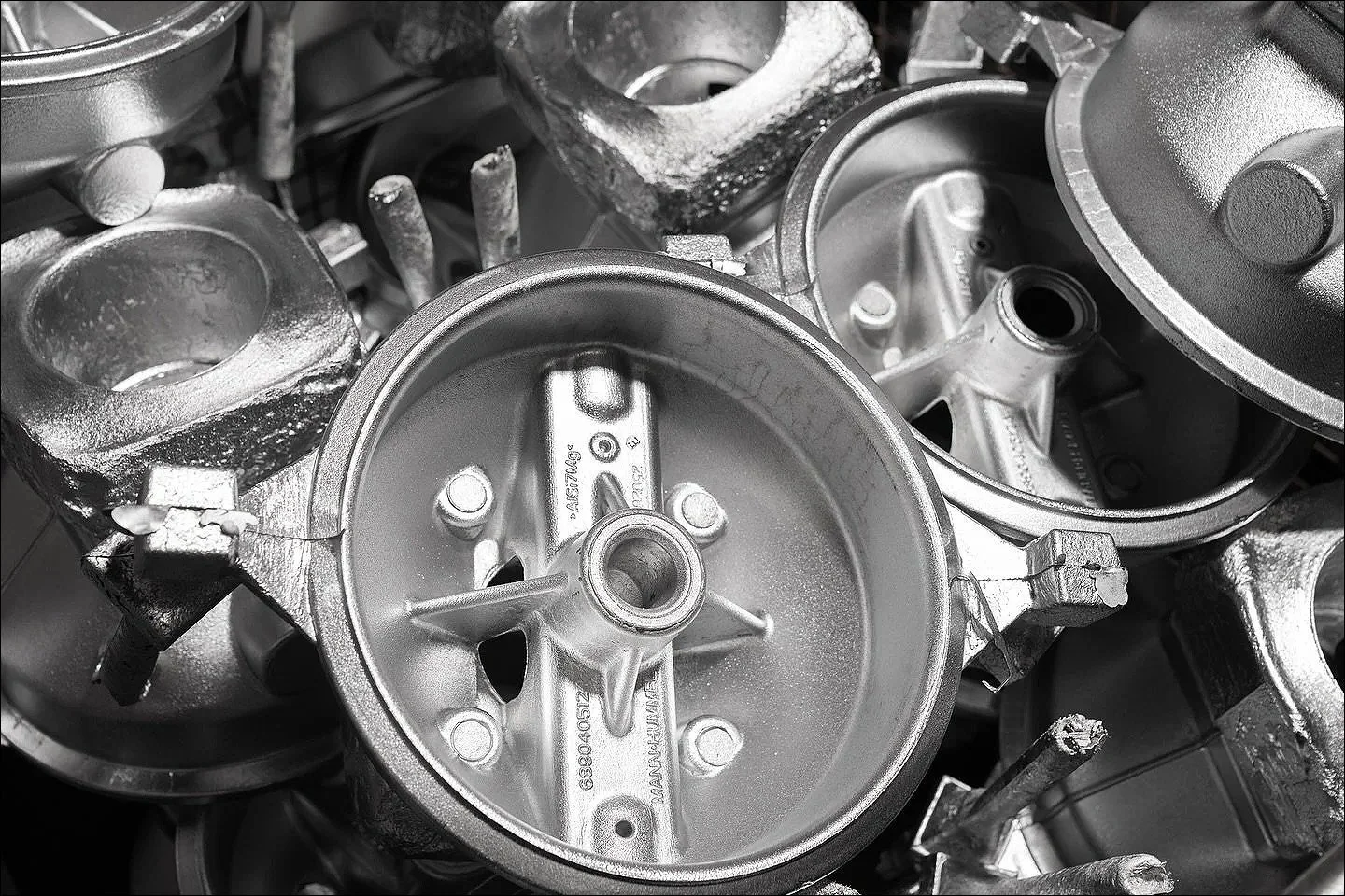 Black and white close-up of stacked metallic industrial components or castings.