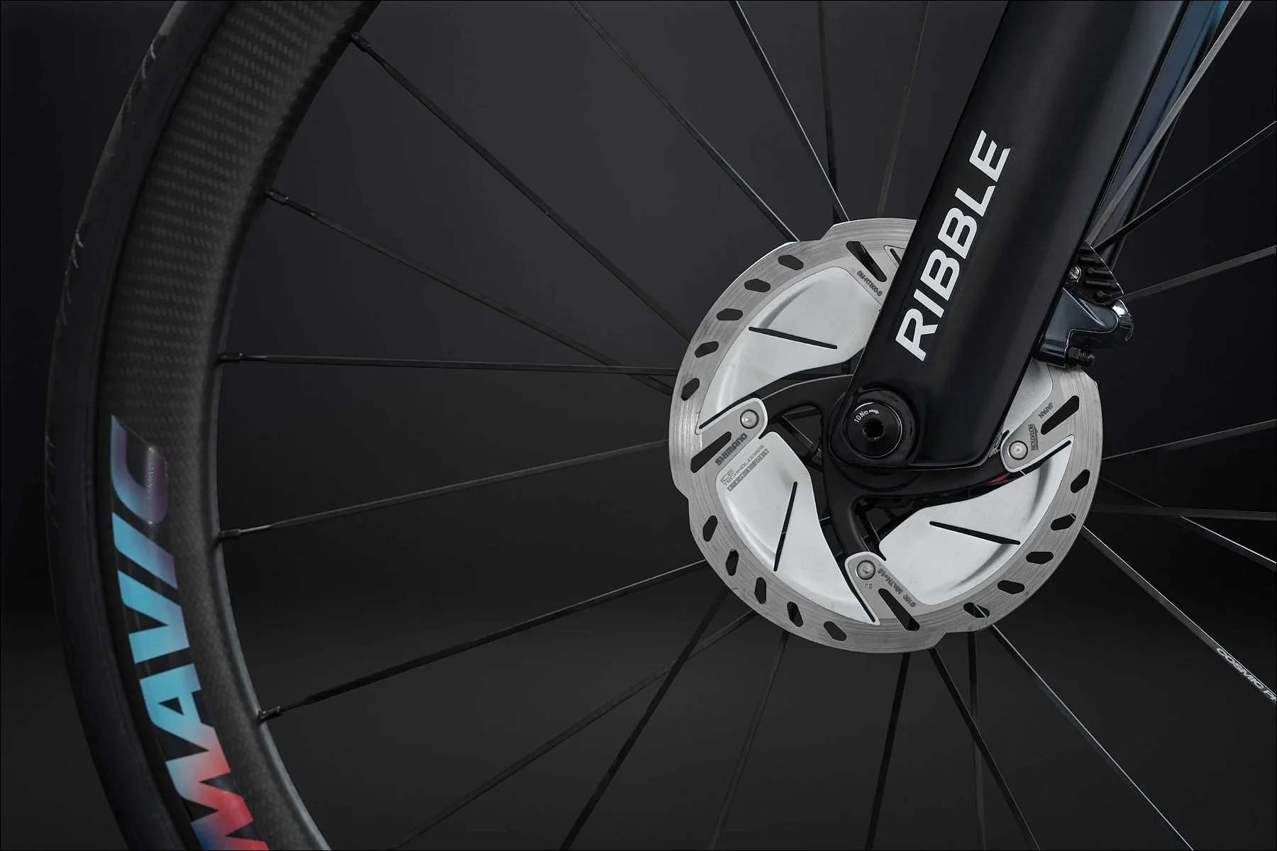 Close-up of a bicycle front wheel with Mavic rim and disc brake rotor attached to a black fork labeled Ribble.
