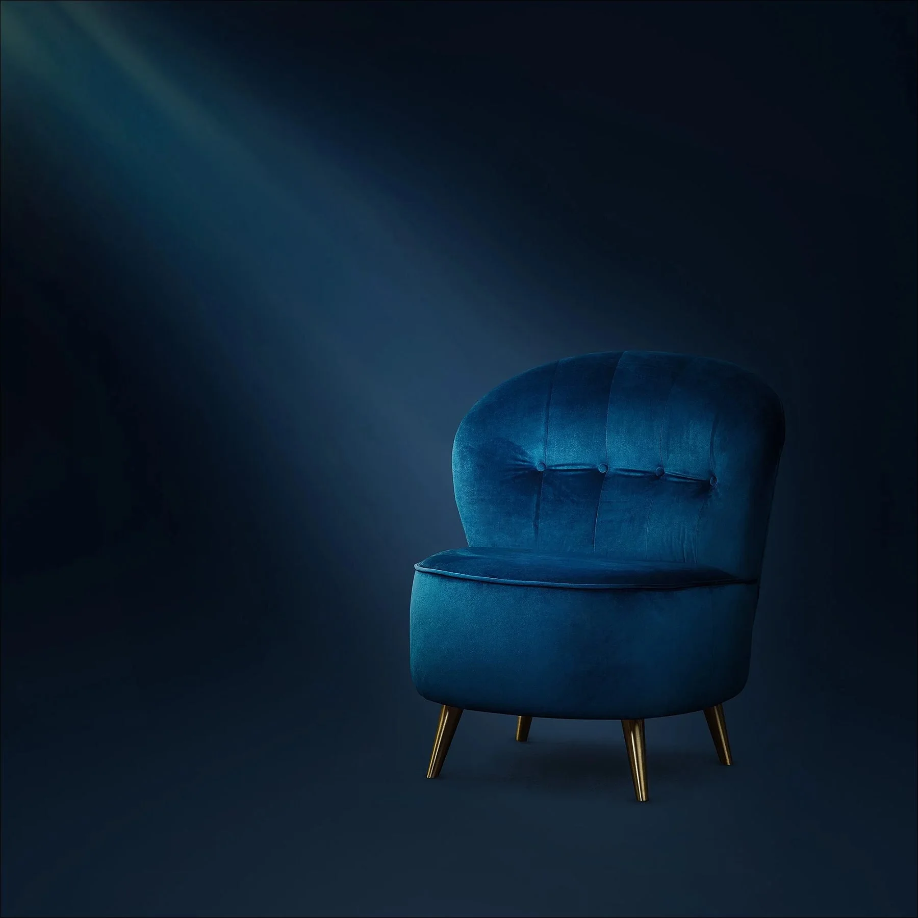 Blue velvet armchair displayed in a dark studio with dramatic spotlight lighting.