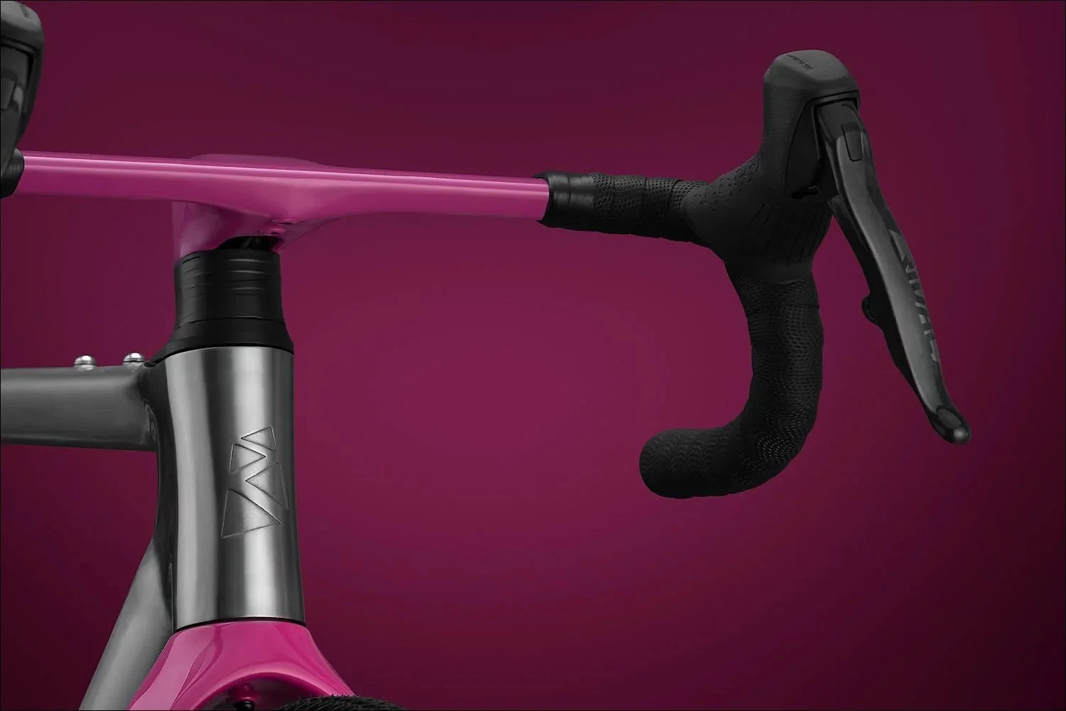 Close-up of a pink bicycle handlebar and stem with black brake lever against a magenta background.