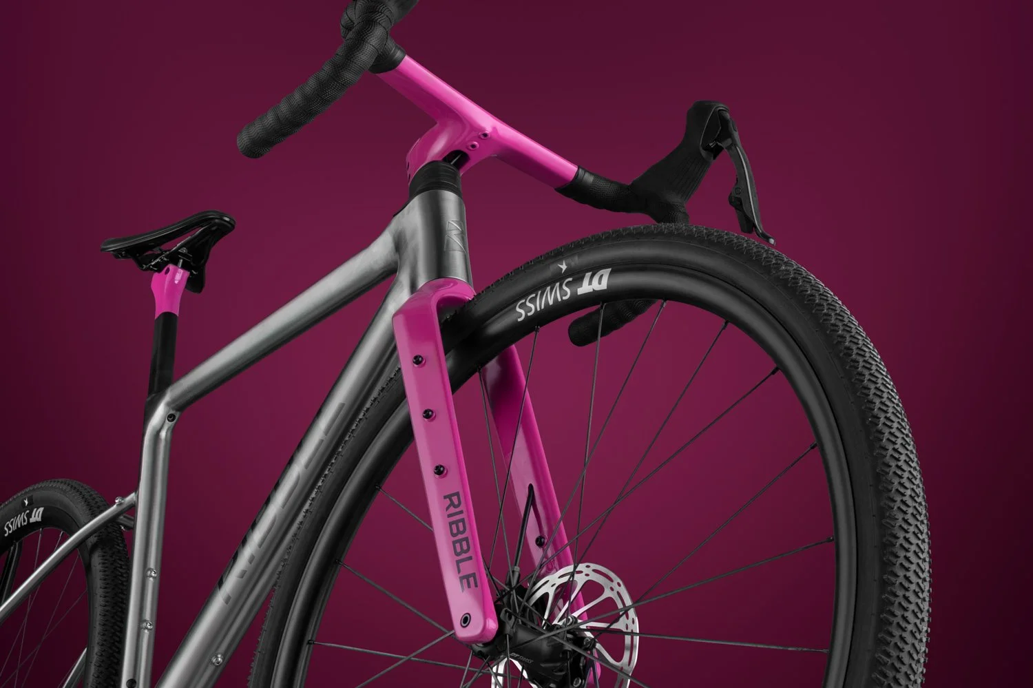 Three-quarter view of the Ribble Allroad's integrated cockpit and metallic pink fork on a titanium-colored frame.