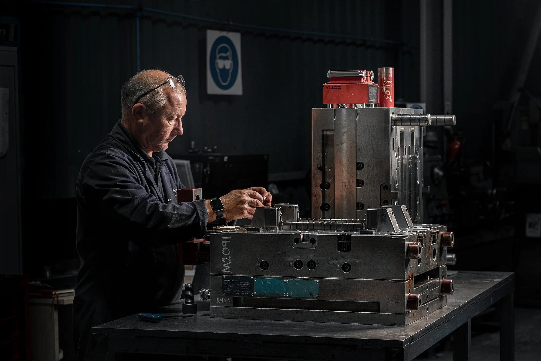 Engineer working on a large industrial machine in a dimly lit workshop.