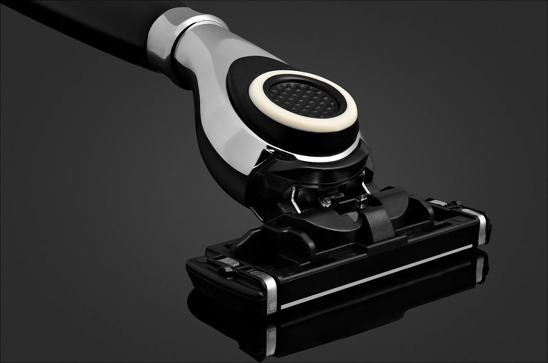Black and silver vacuum cleaner head with an ergonomic handle attachment displayed on a dark background.