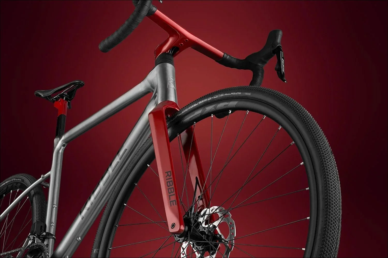 Grey and red bike product photograph highlighting the front half of the bike against a dark red background.