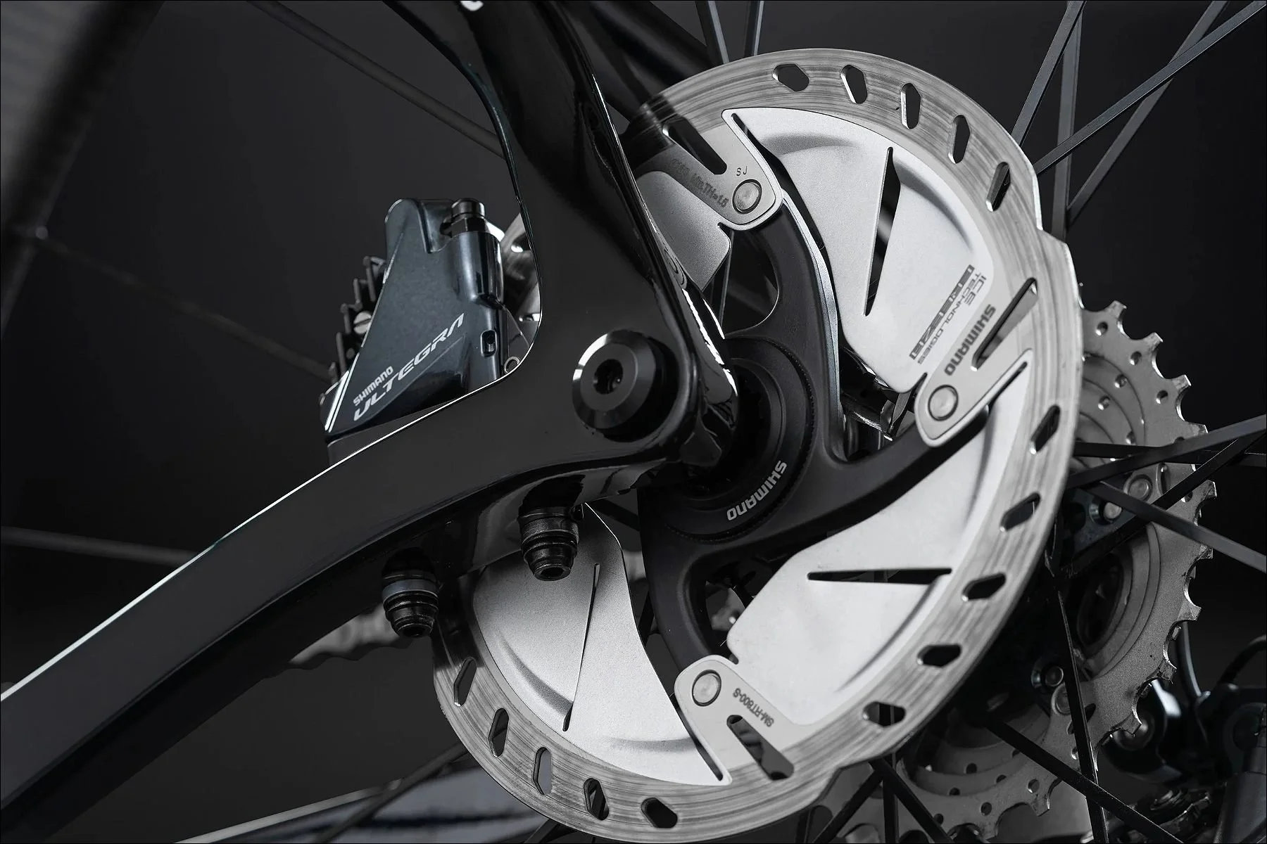 Macro close-up of bicycle disc brake rotor and caliper showing mechanical details in a studio setting.