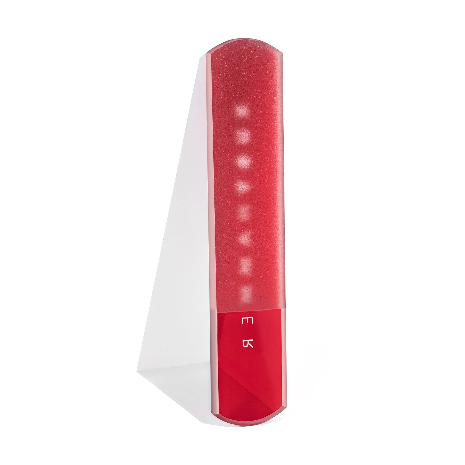 Red rectangular sculptural object with an illuminated vertical line and gradient design, displayed on a white stand against a white background.