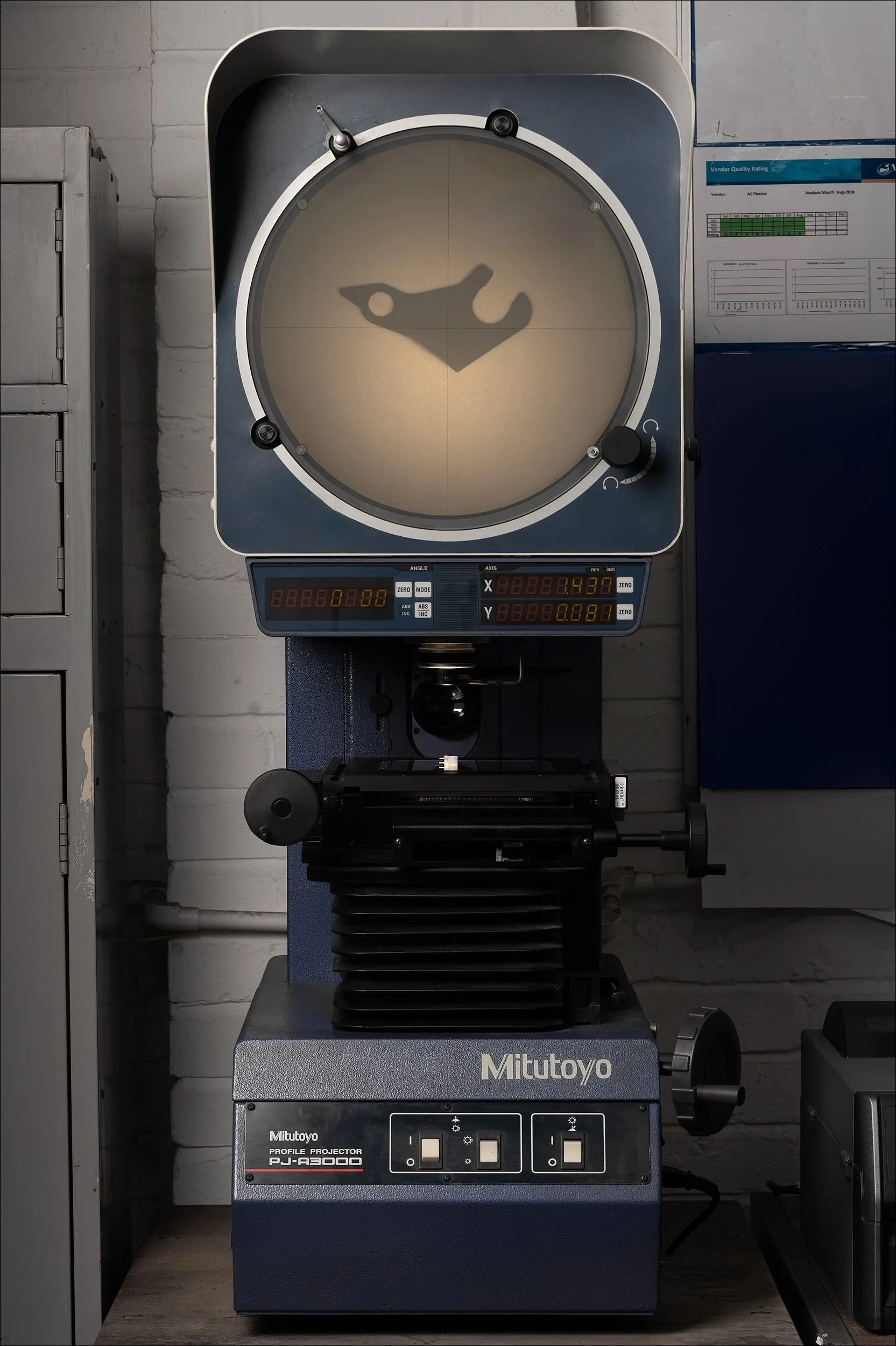 Industrial optical comparator or measurement machine with a circular viewing screen used for inspecting parts.