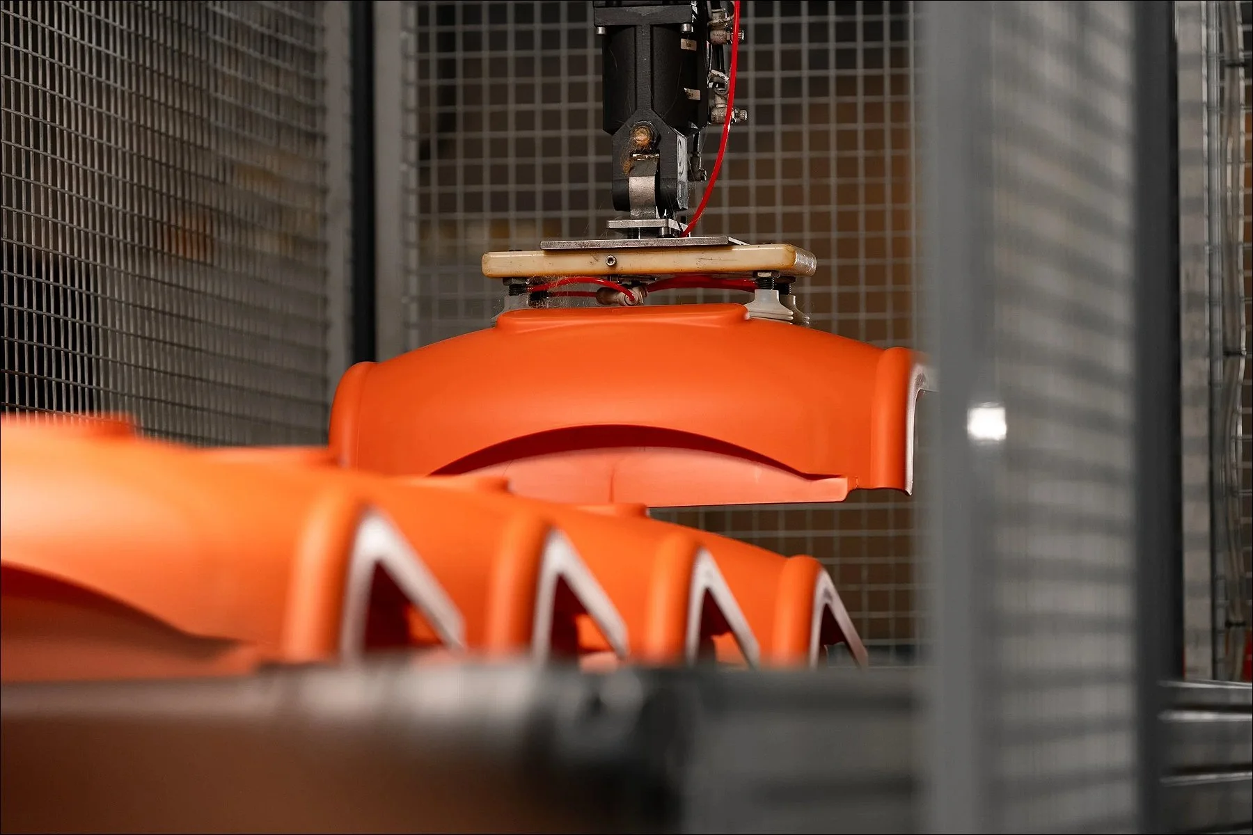 Bright orange plastic components arranged inside industrial manufacturing machinery.