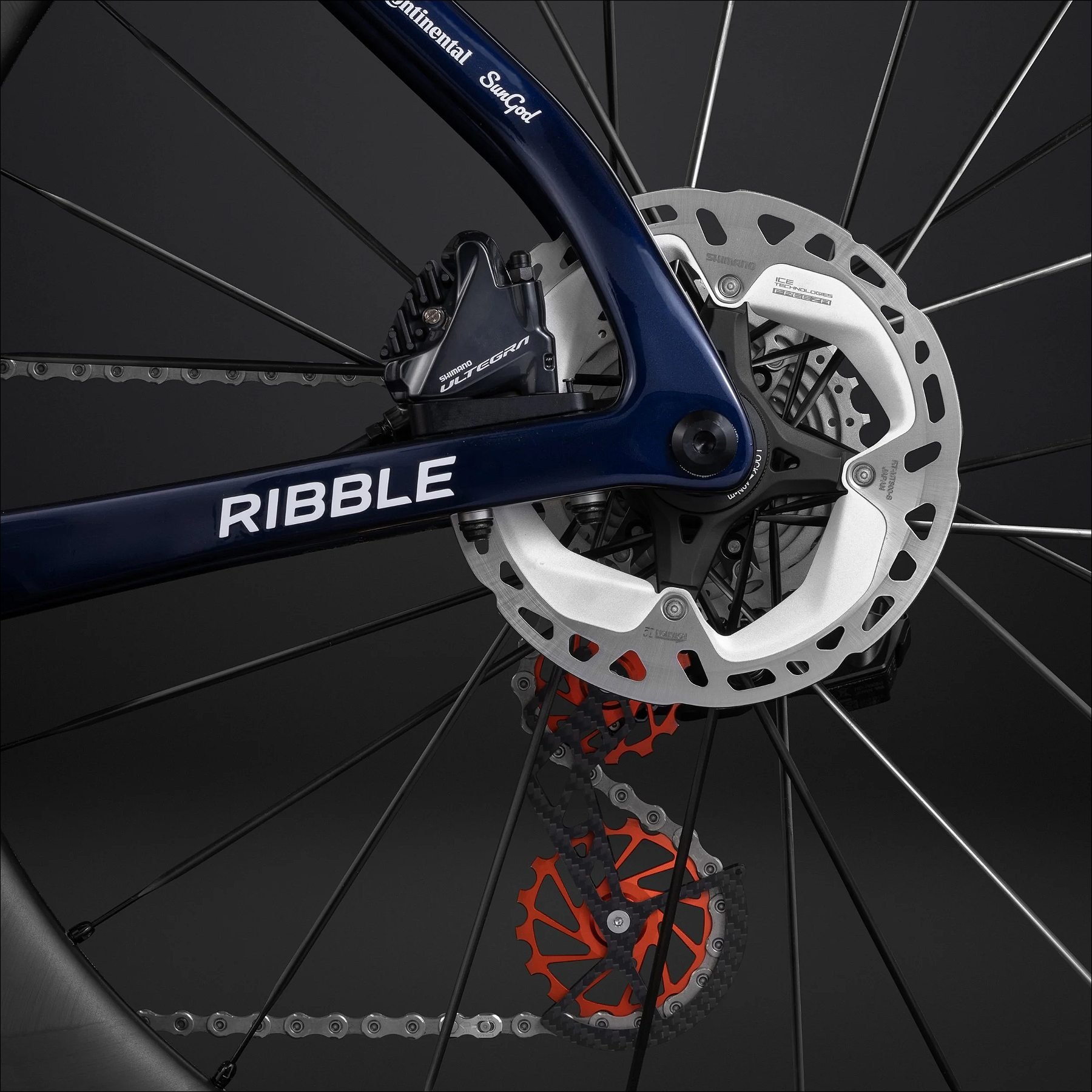 Close-up of a bicycle disc brake rotor and blue fork with Ribble branding against a dark background.