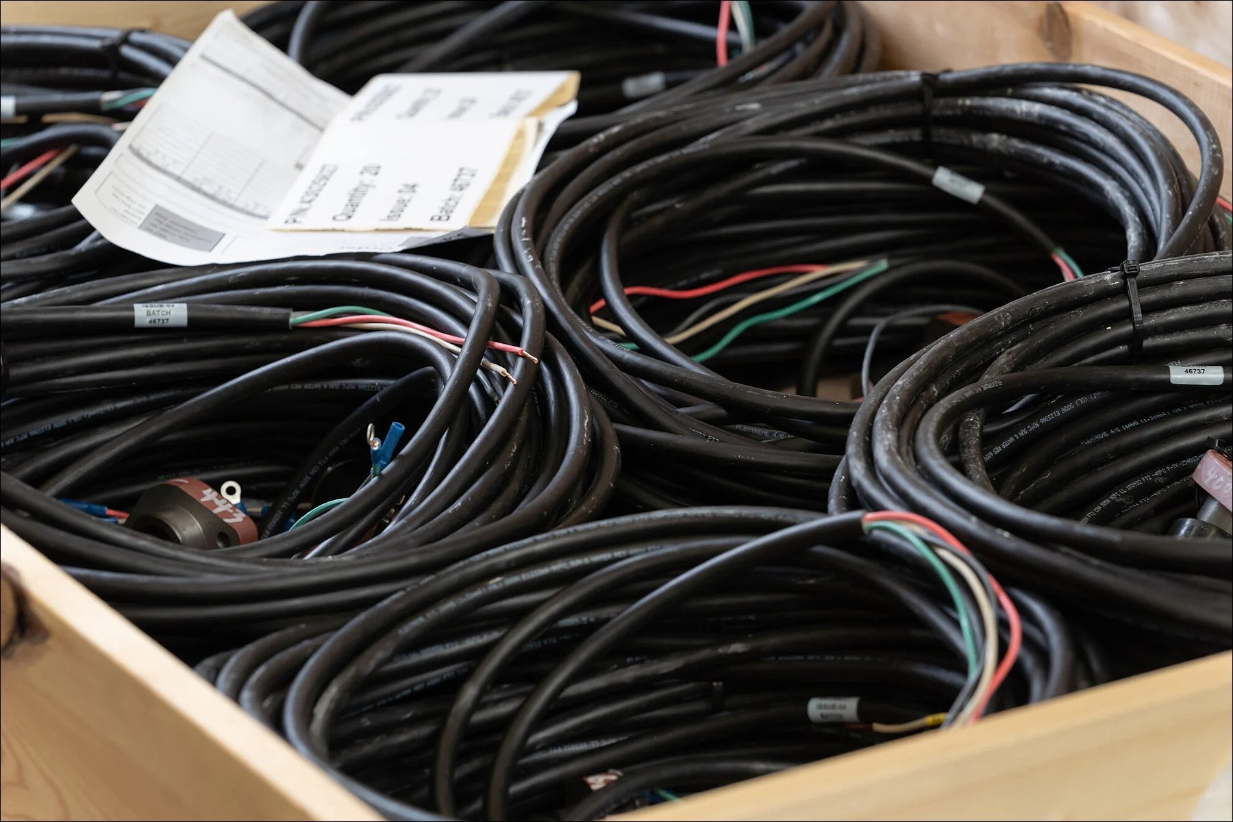 Crate filled with organized electrical cables and wire harnesses in a manufacturing setting.