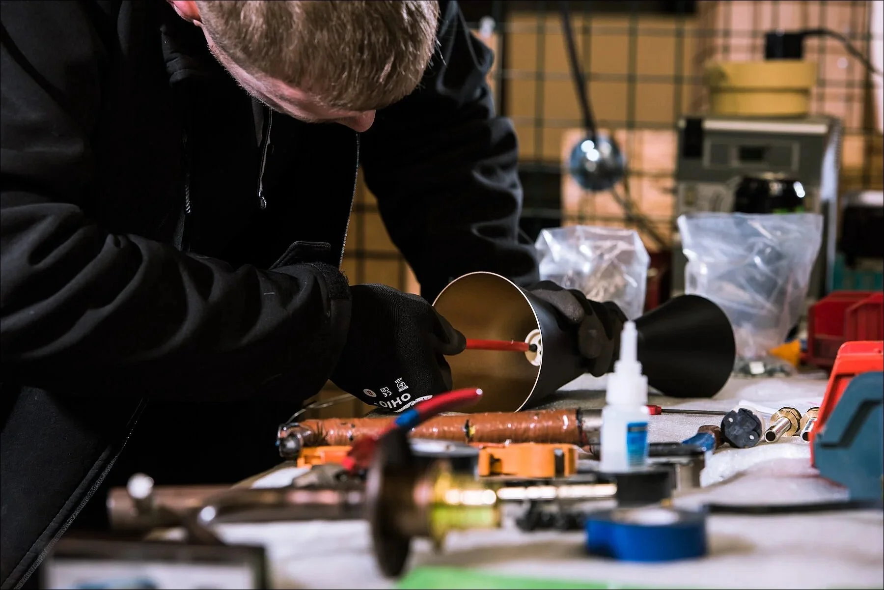Industrial worker using tools to assemble machinery components in a workshop.