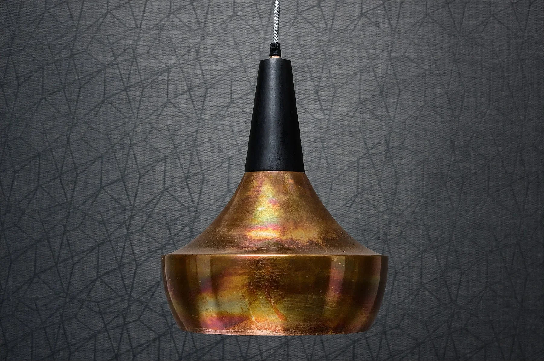 Metal plumb bob with a black tip displayed against a textured grey background