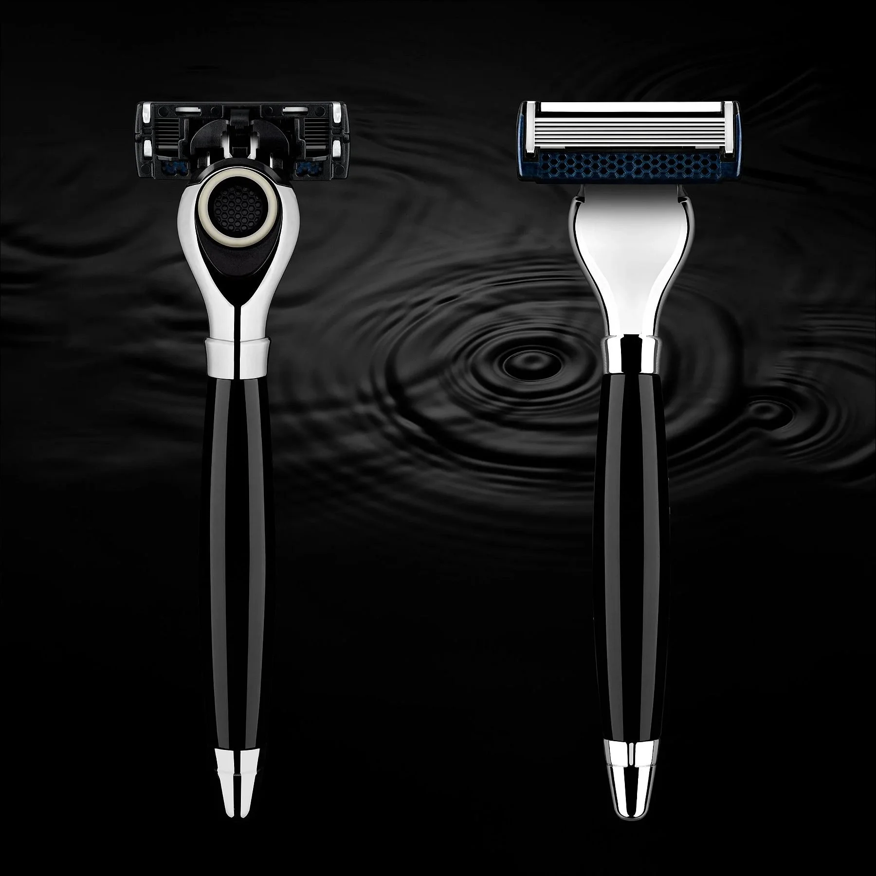 Two sleek black and silver razors displayed upright on a black background with water ripples