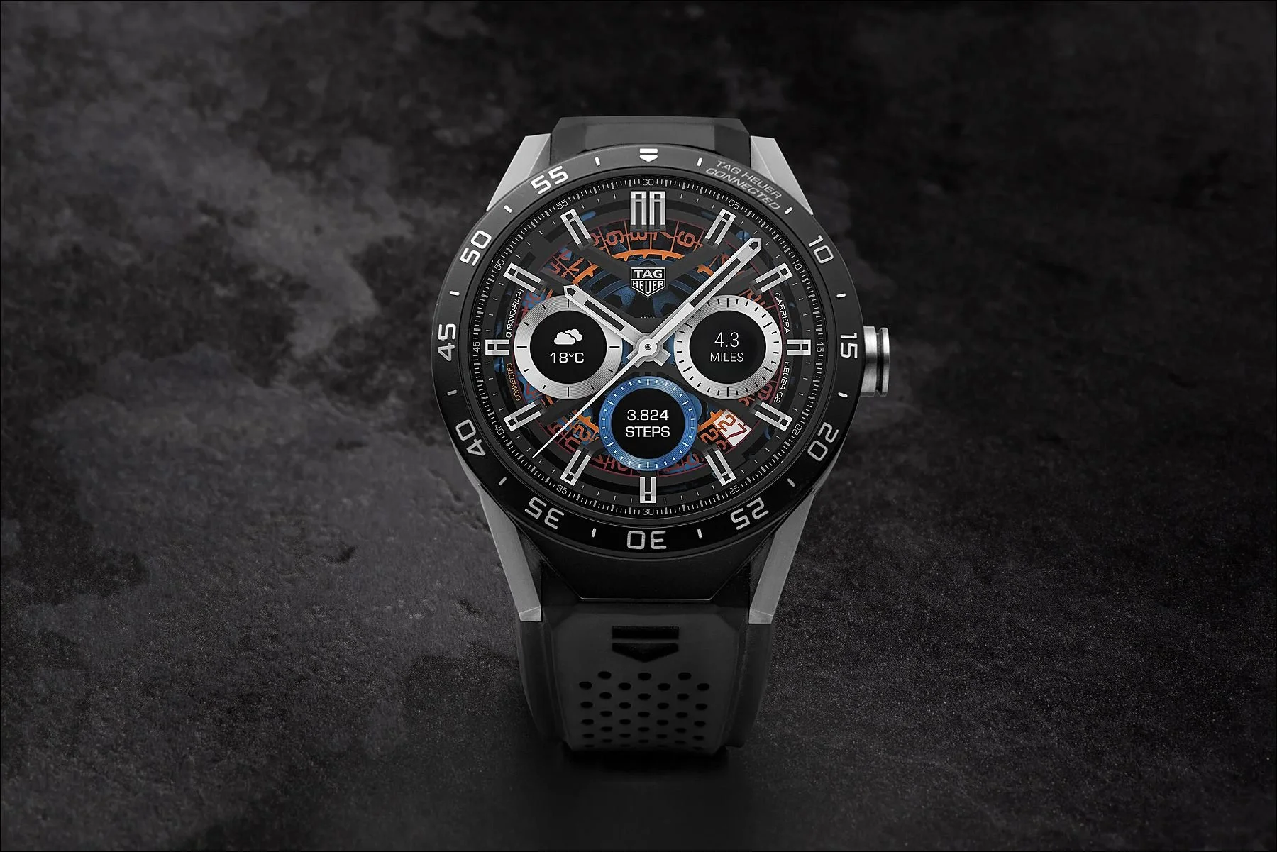 Front view of a black and silver chronograph watch with multiple sub-dials on a dark textured background
