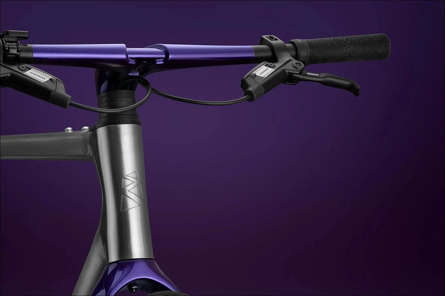 Front view of purple bicycle handlebars and brake levers against a purple gradient studio background.