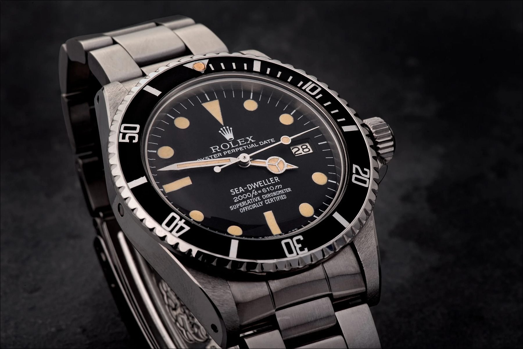 Silver diver's watch with black dial and rotating bezel displayed on a dark background