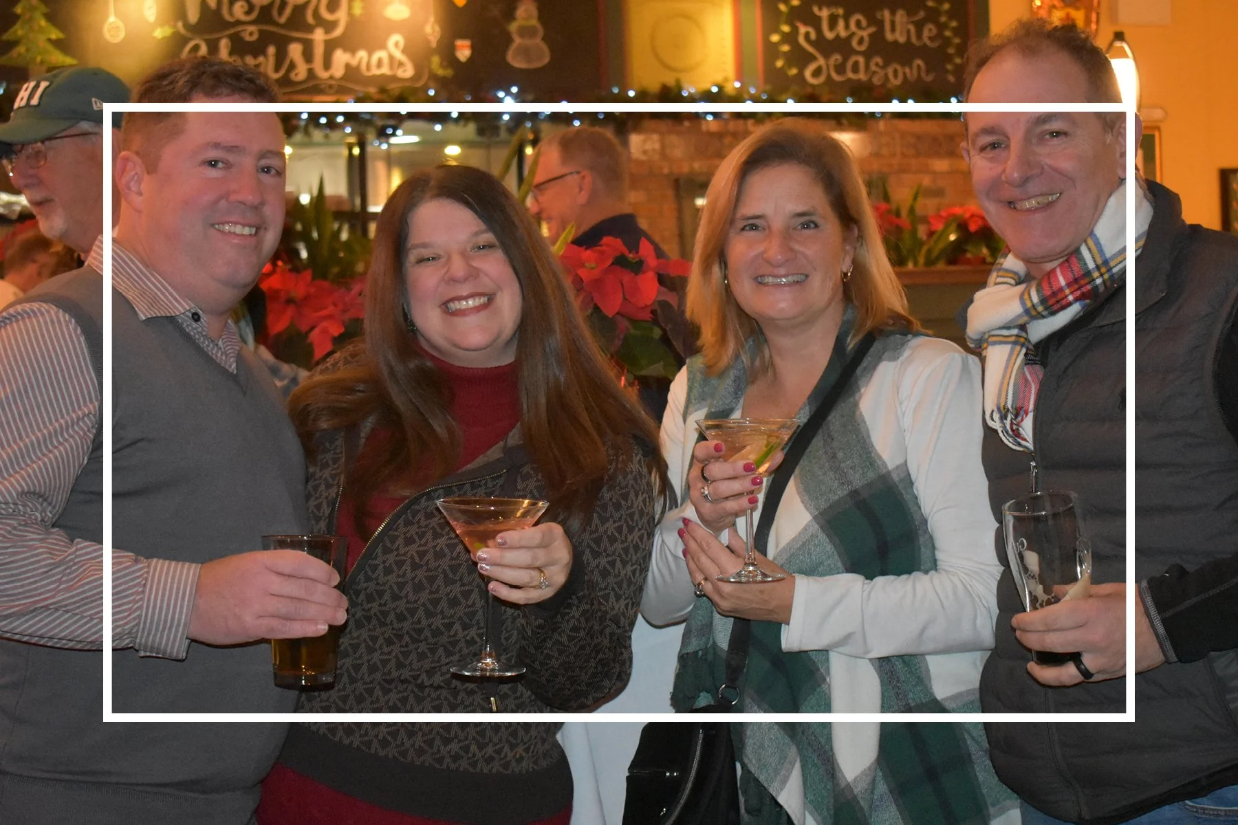 two men and two women in dim but warmly lit room holding drinks wearing holiday themed clothing