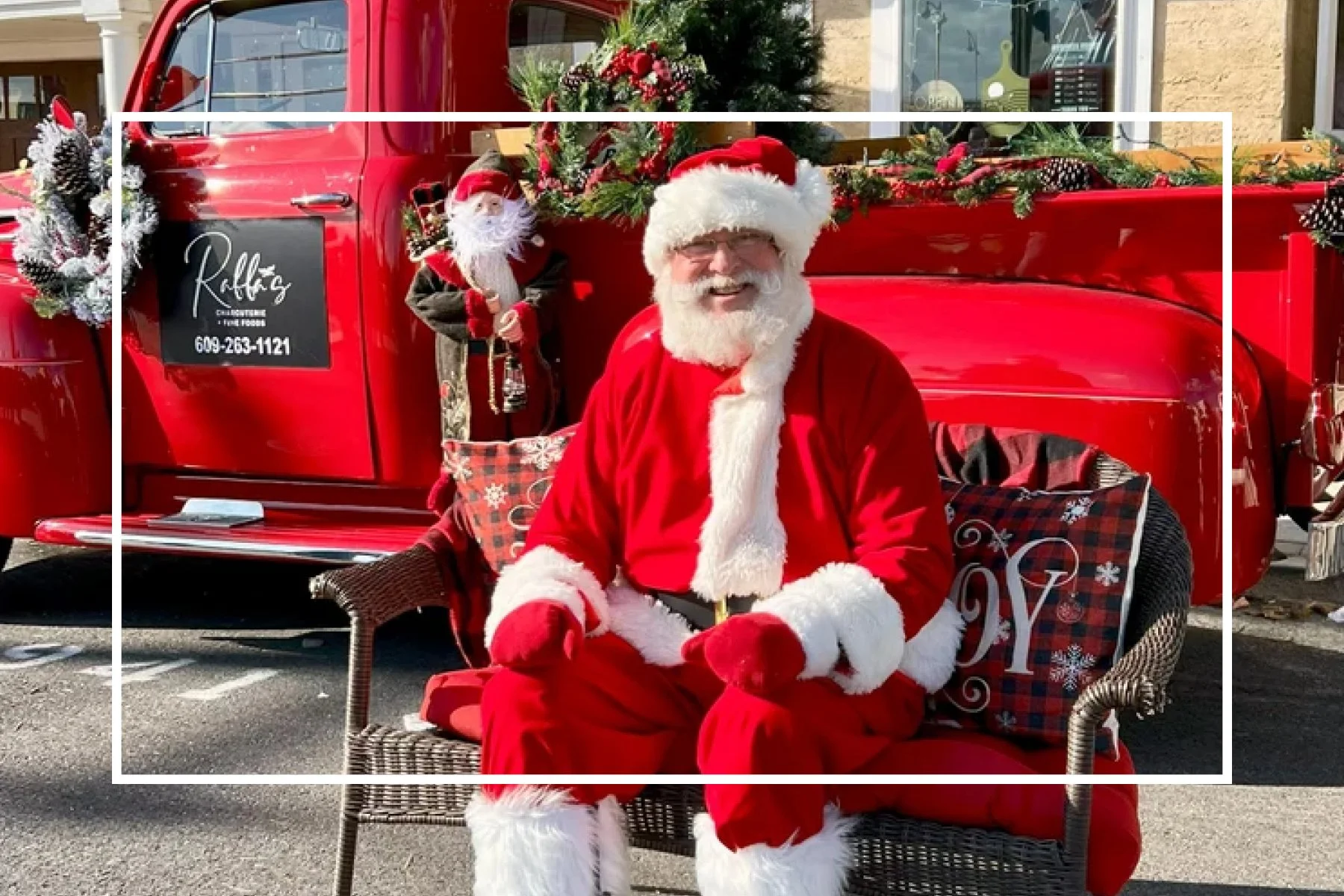 santa claus in front of red old style pickup truck decorated with greenery