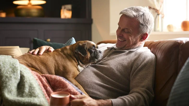 man and dog rest comfortably on couch