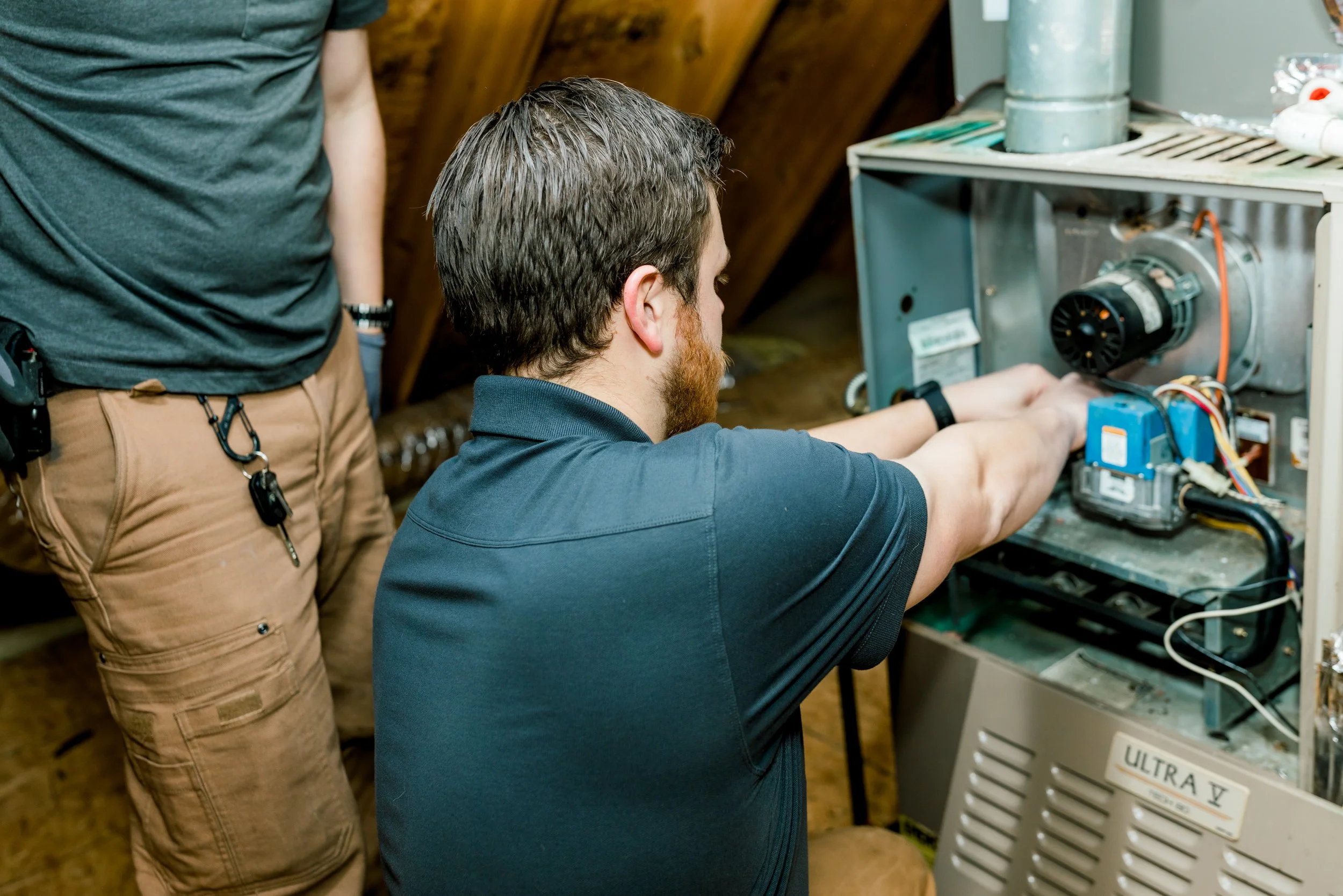HVAC technicians working on a furnace system.