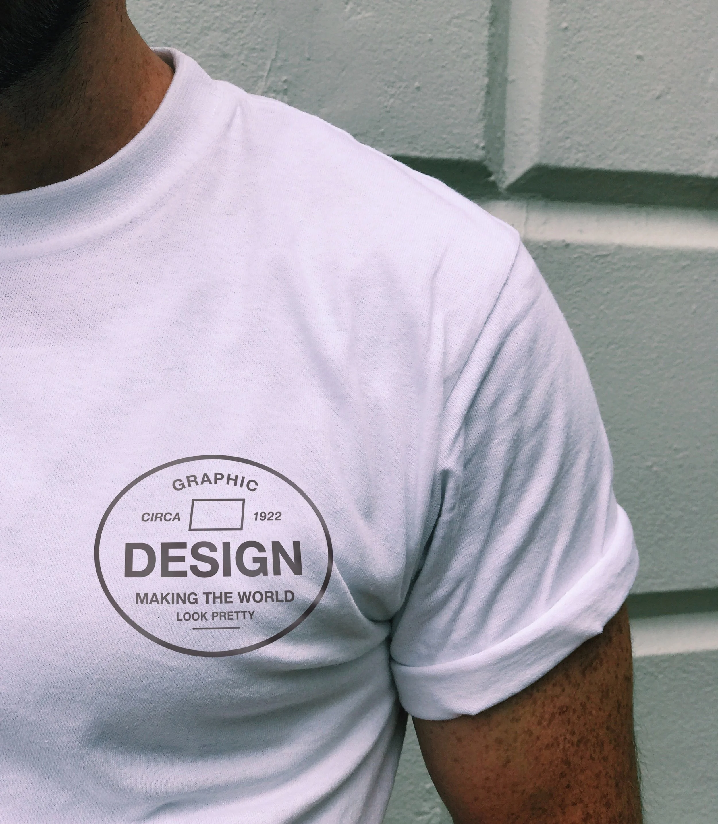 White T-shirt with a graphic design on the chest that reads 'Circa 1922 Graphic Design Making the World Look Pretty' inside a circular outline.