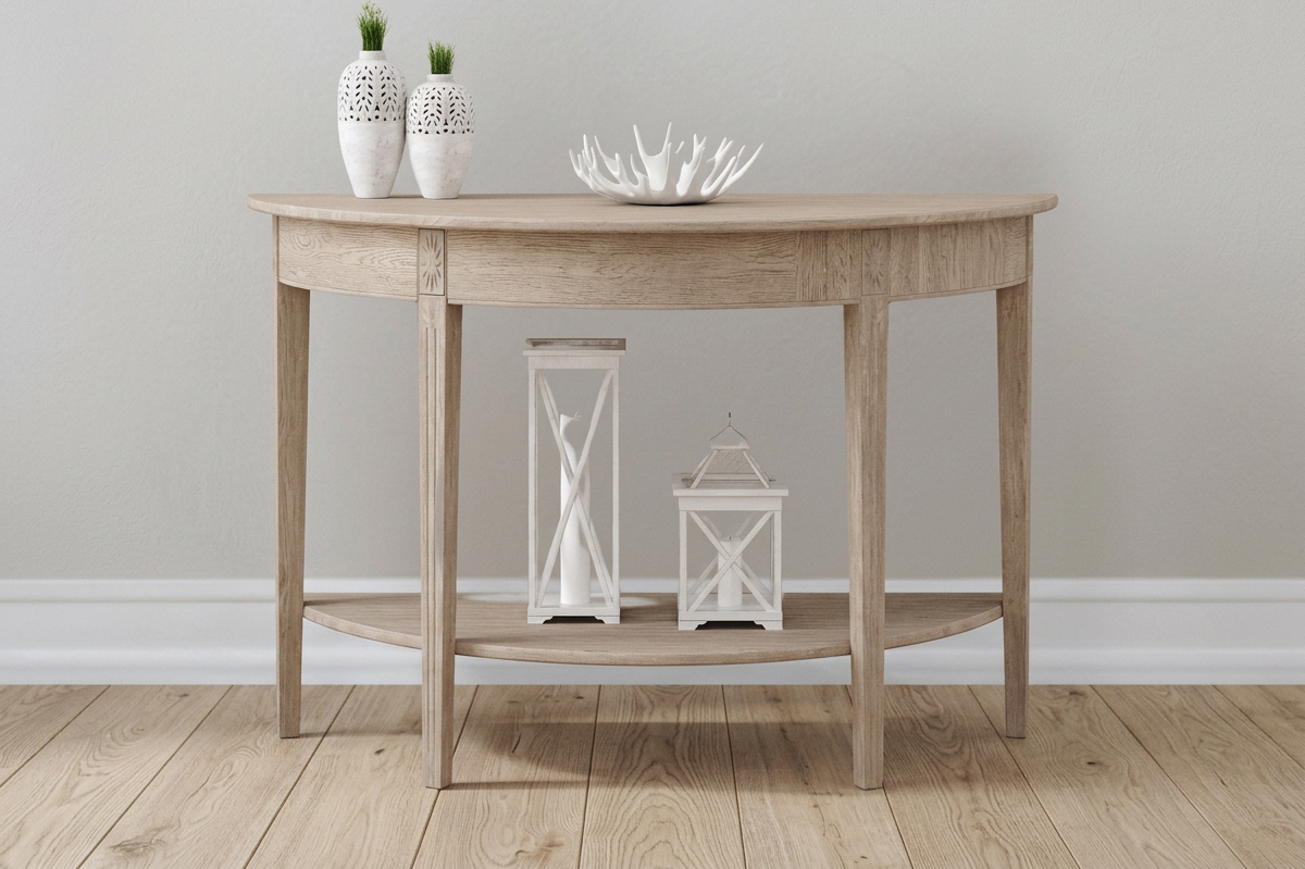 Wooden console table with white decorative vases with green plants, a white coral sculpture, and candle lanterns against a light-colored wall.