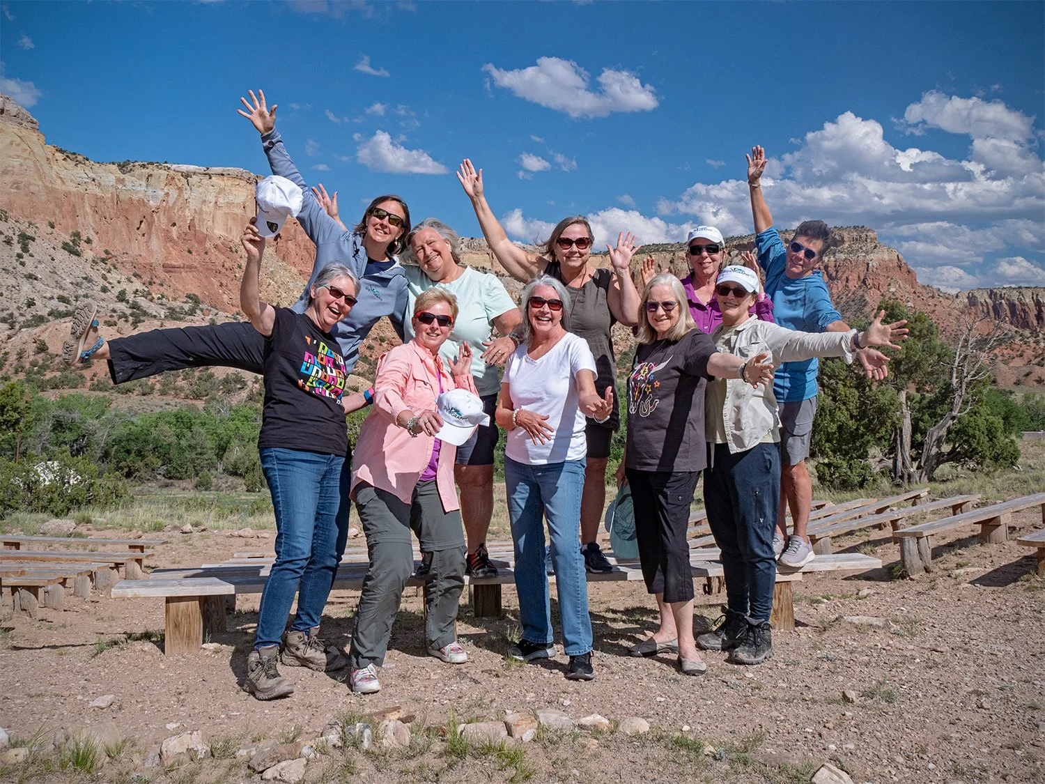 Group of women posing outdoors with red rock formations and blue sky in the background.