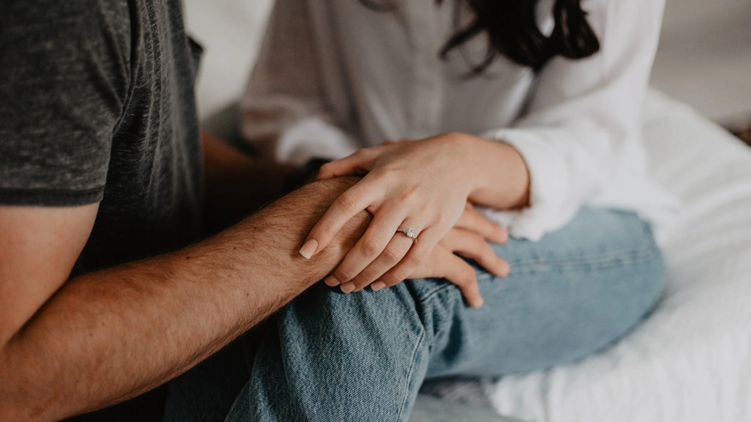 woman wearning engagement ring holding hands with man