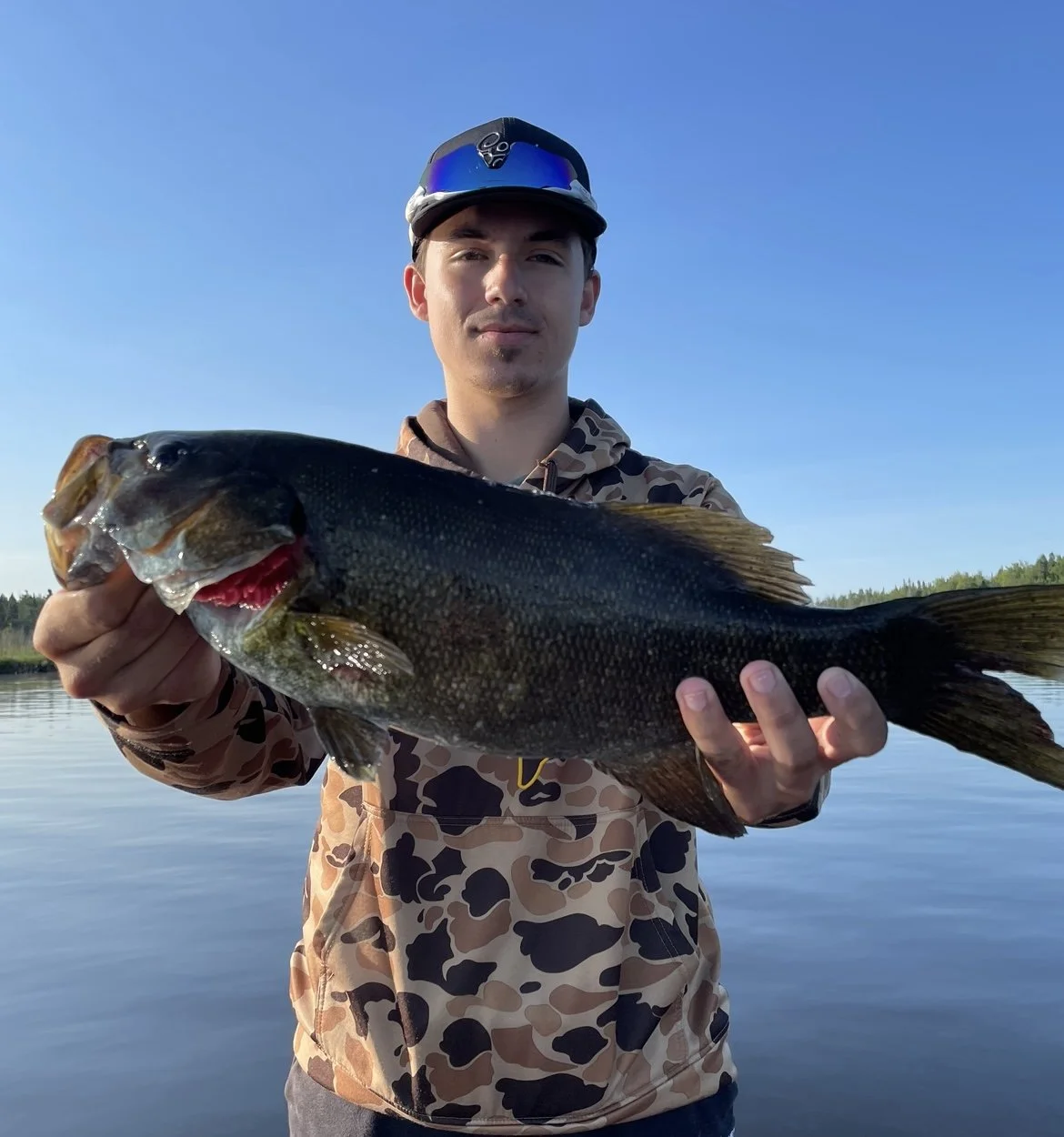 Bass Fishing Guide Services - Fishing Guide - Twin Lakes, MI - Person holding a large bass fish near a lake.