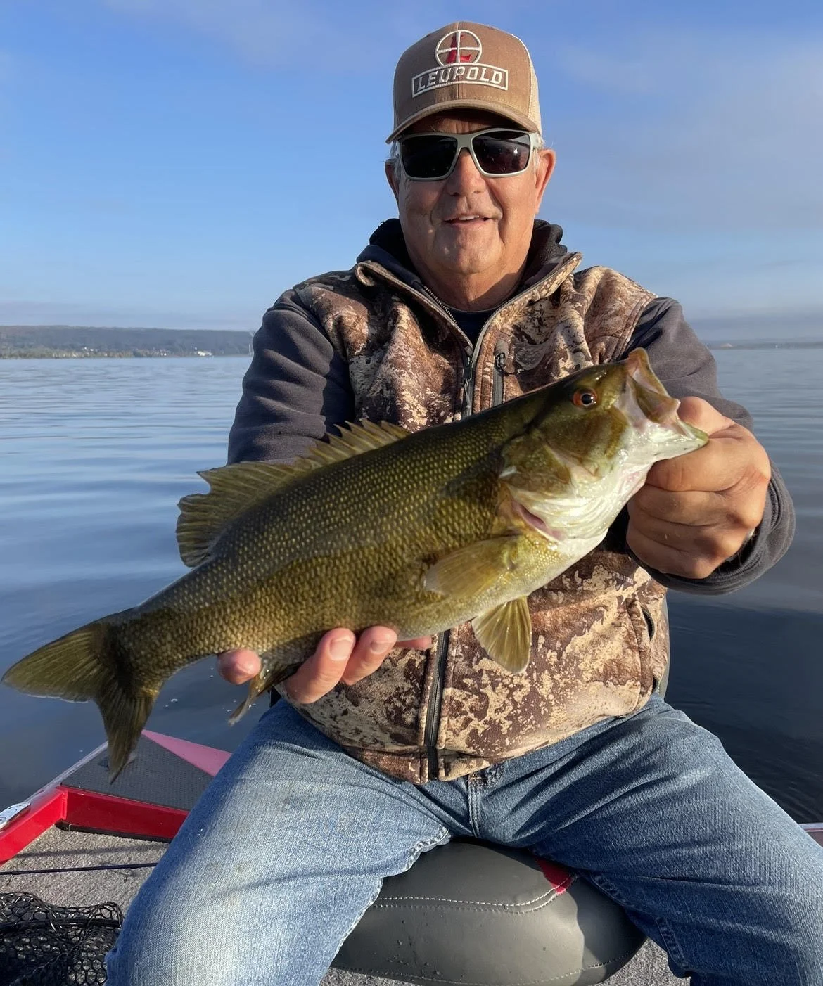 Man holding a largemouth bass on a boat.
