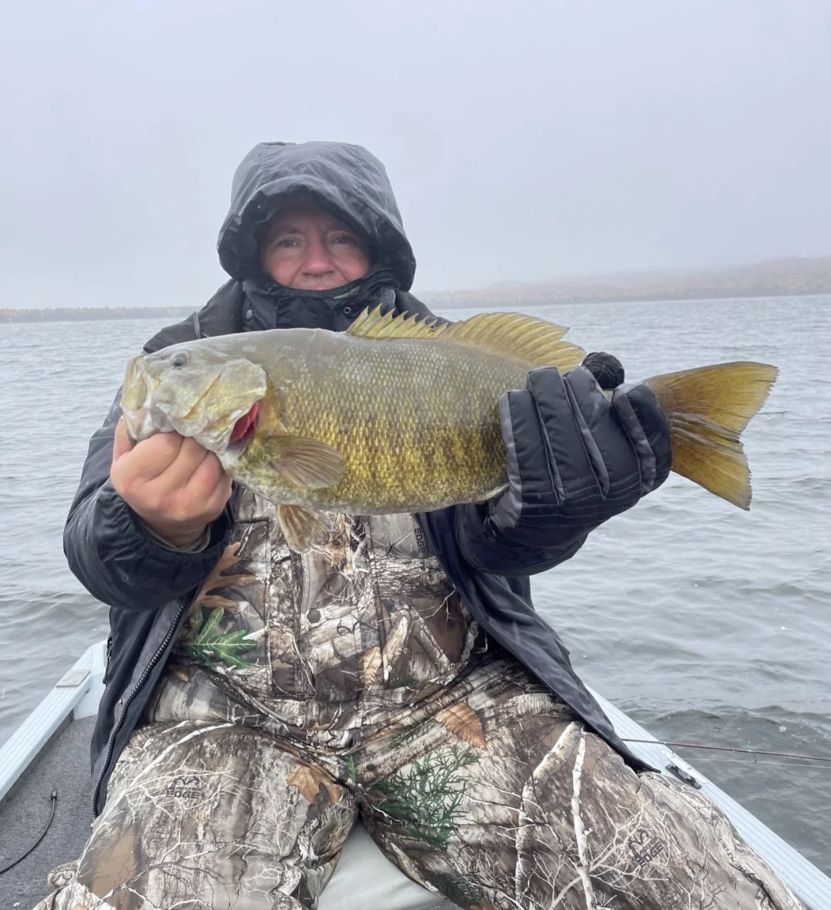 Person in camo holding a large fish on a boat