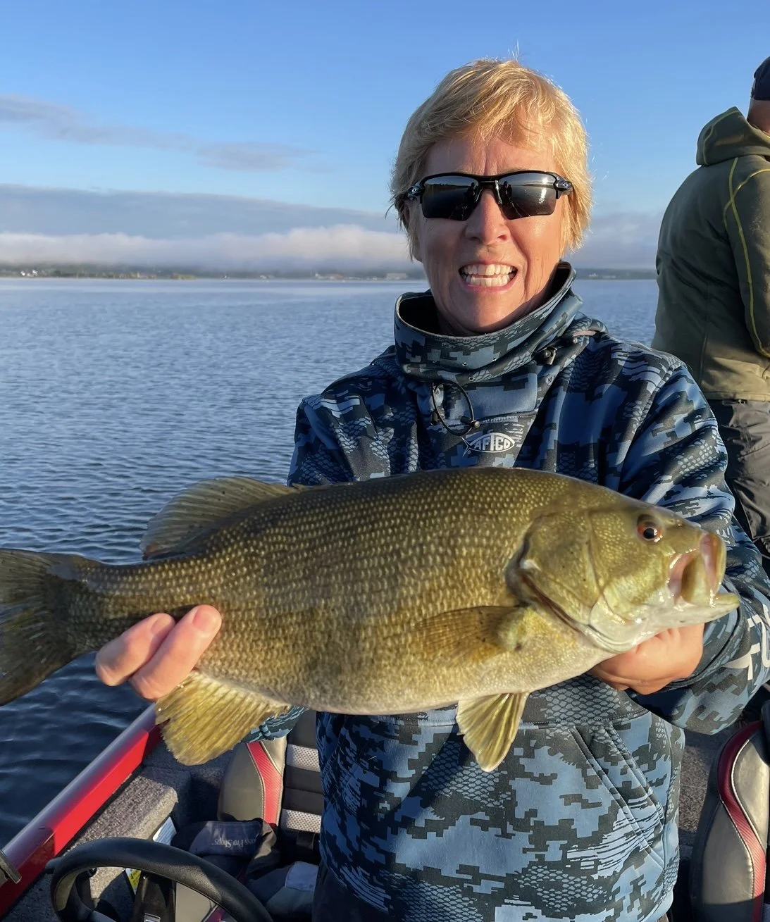 Bass Fishing Guide Services - Fishing Guide - Calumet, MI - Person holding a large fish on a boat at a lake