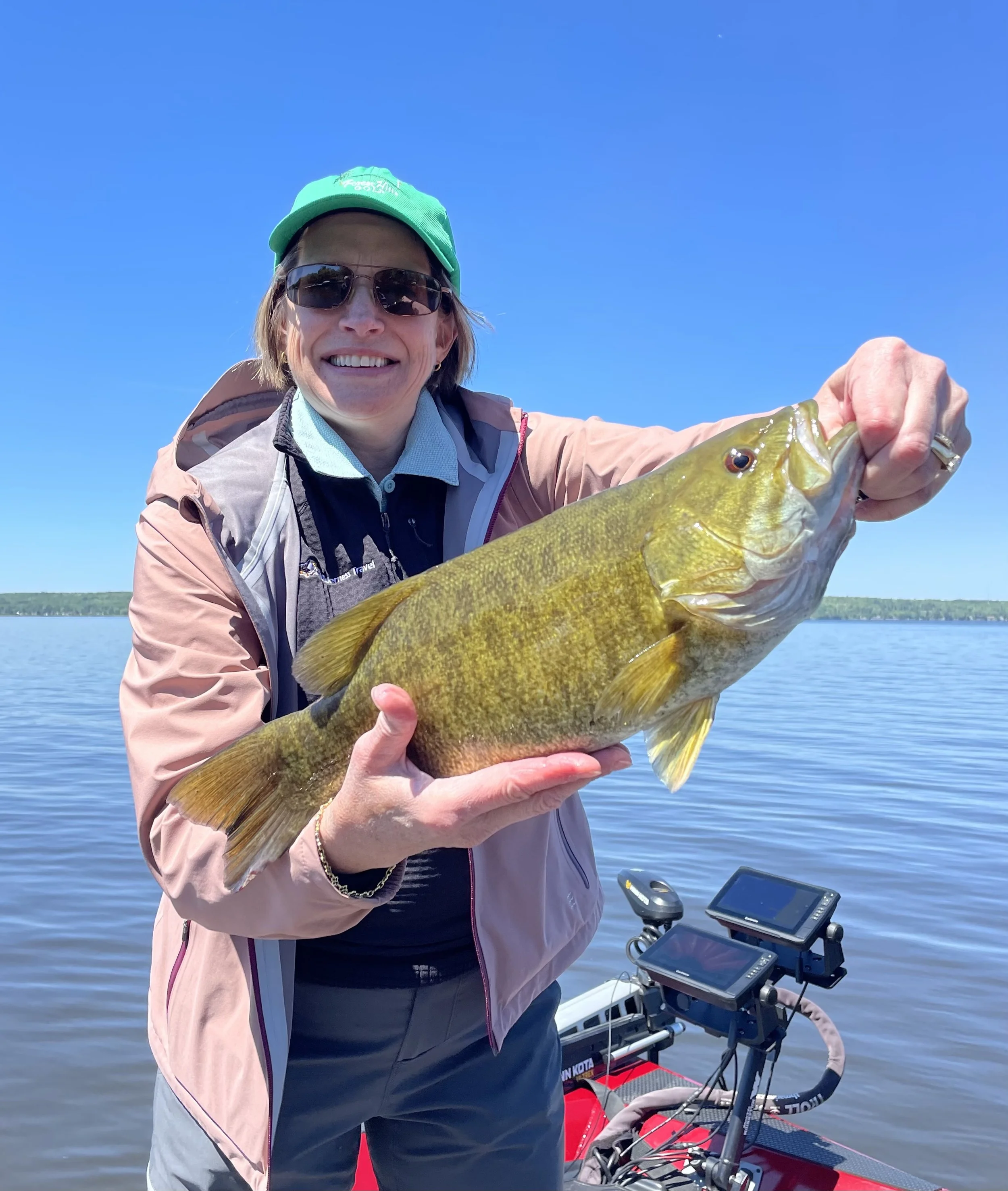 Bass Fishing Guide Services - Fishing Guide - Eagle Harbor, MI - holding a large fish on a boat with water and sky in the background