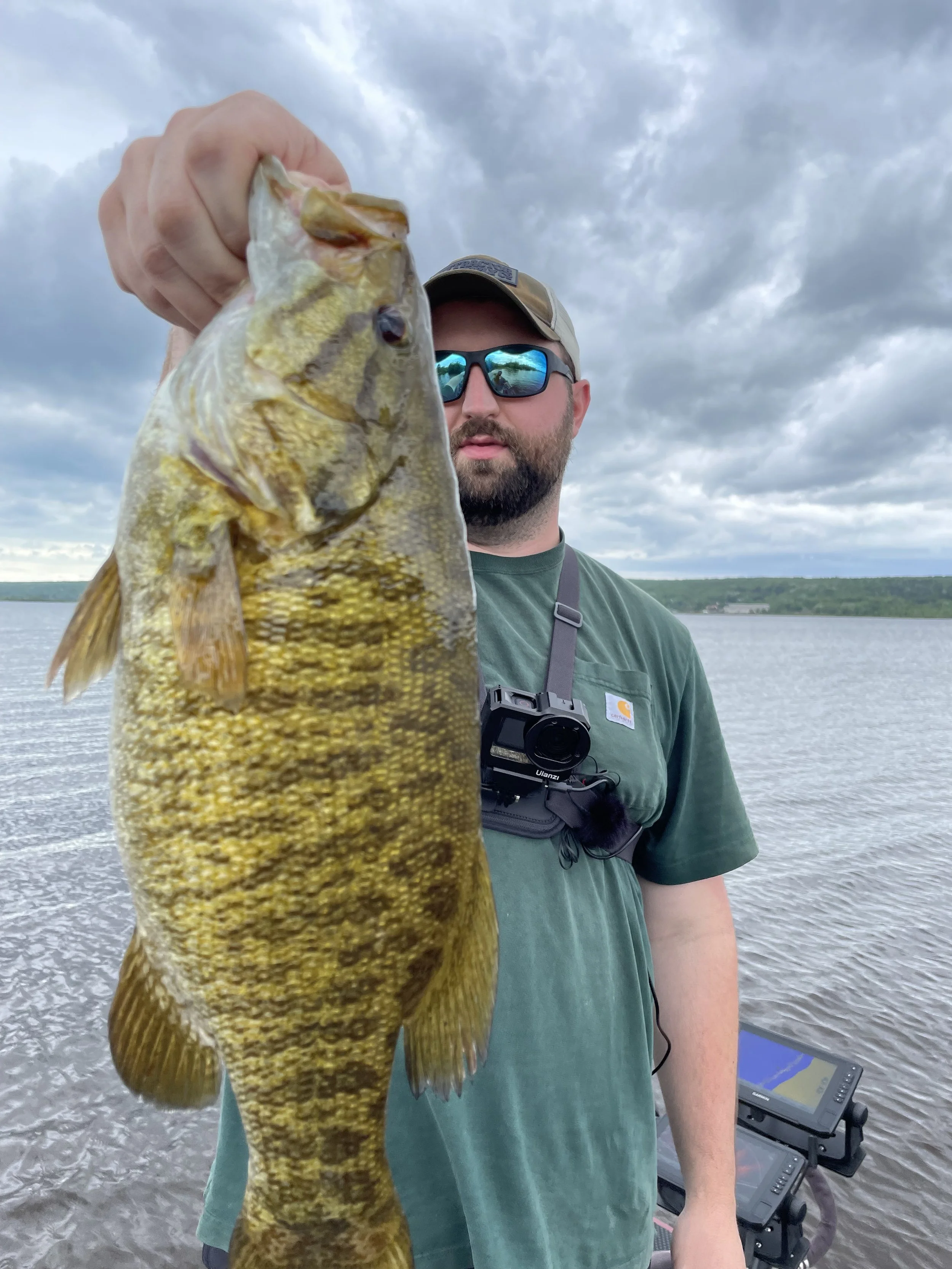 Man holding a bass fish near a lake
