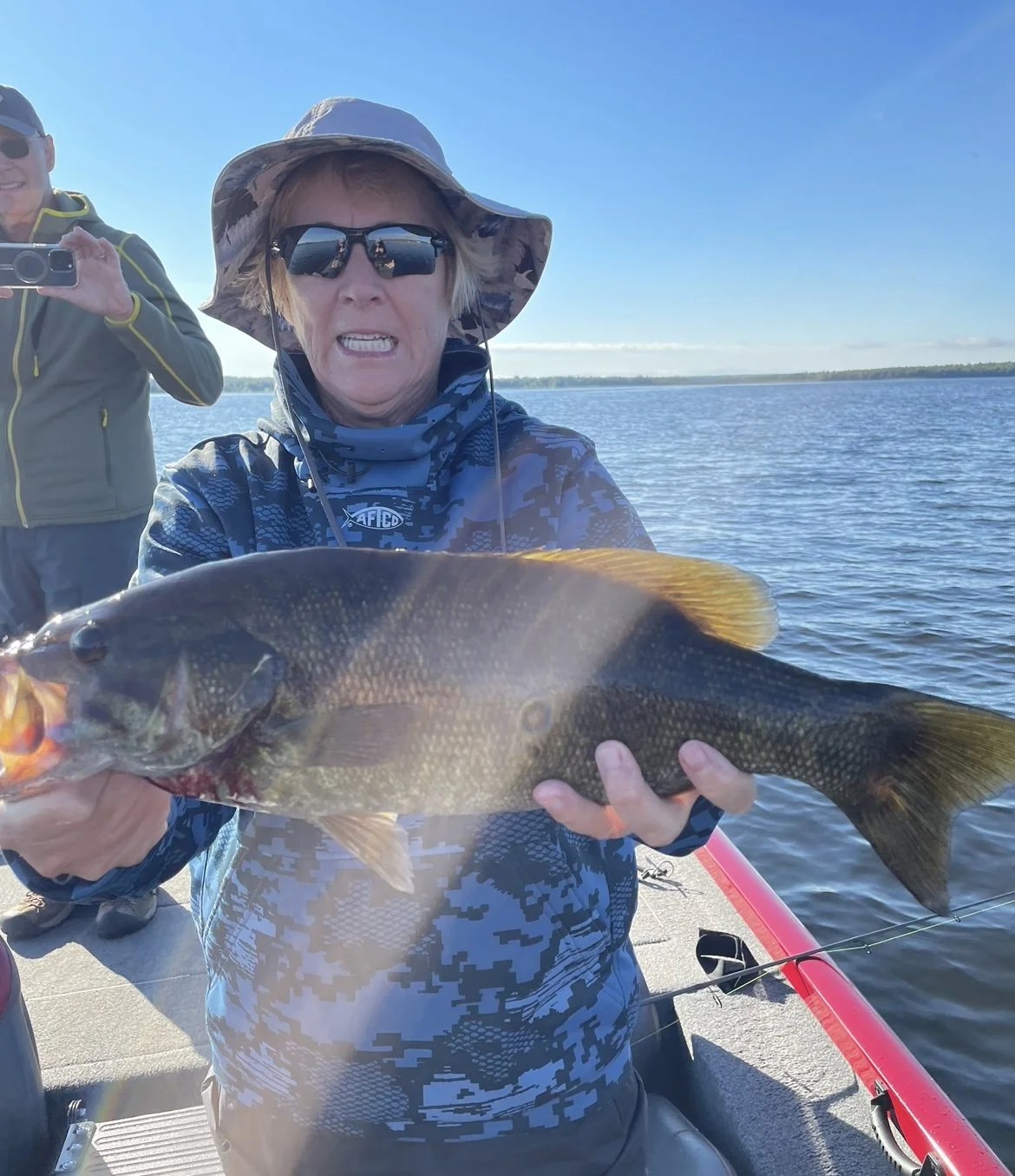 Bass Fishing Guide Services - Fishing Guide - Eagle Harbor, MI - Person holding a large fish on a boat with water in the background.