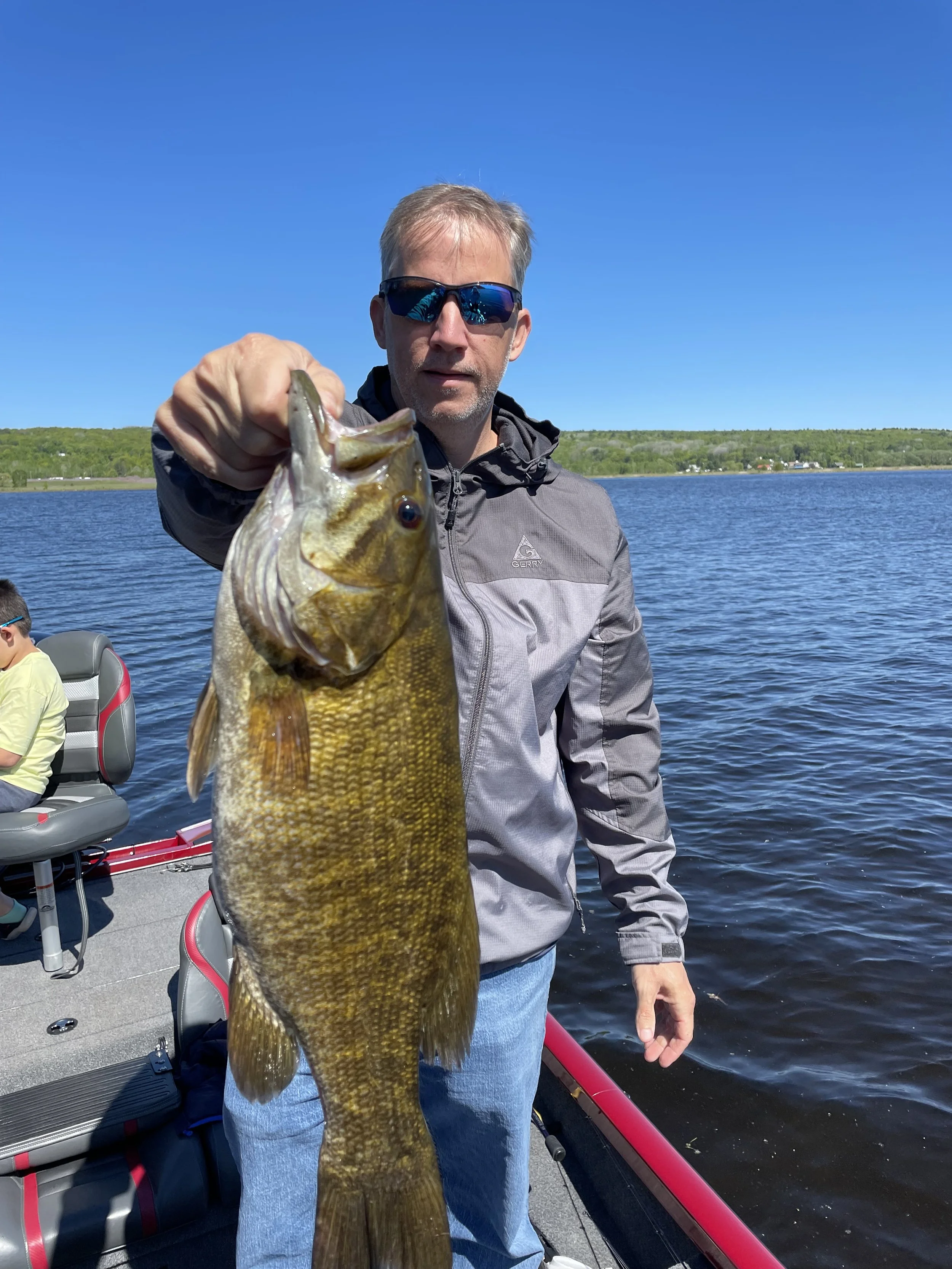 Man holding a large fish on a boat in a lake