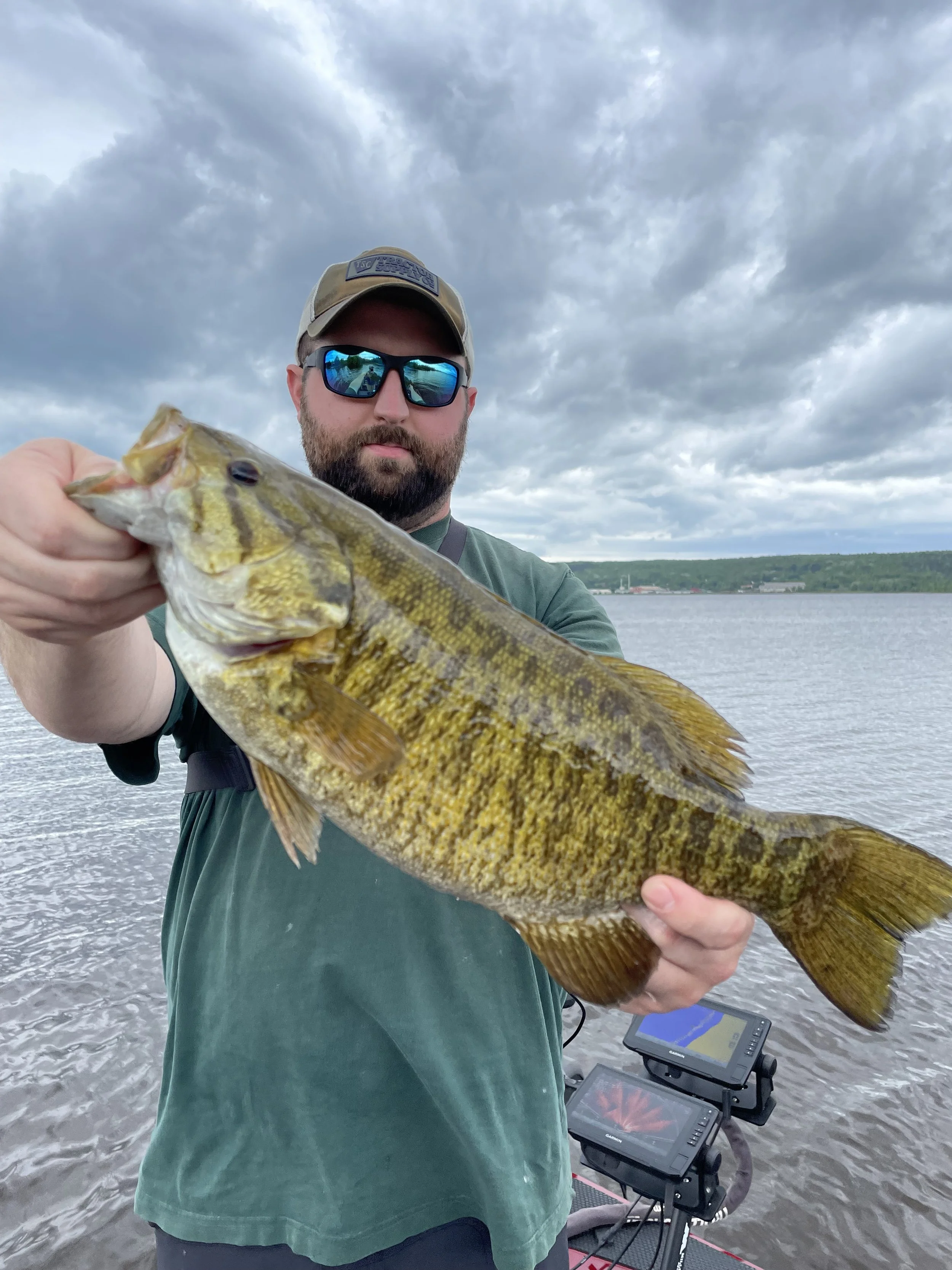 Bass Fishing Guide Services - Fishing Guide - Portage Lake, MI - Man holding a large fish near a body of water