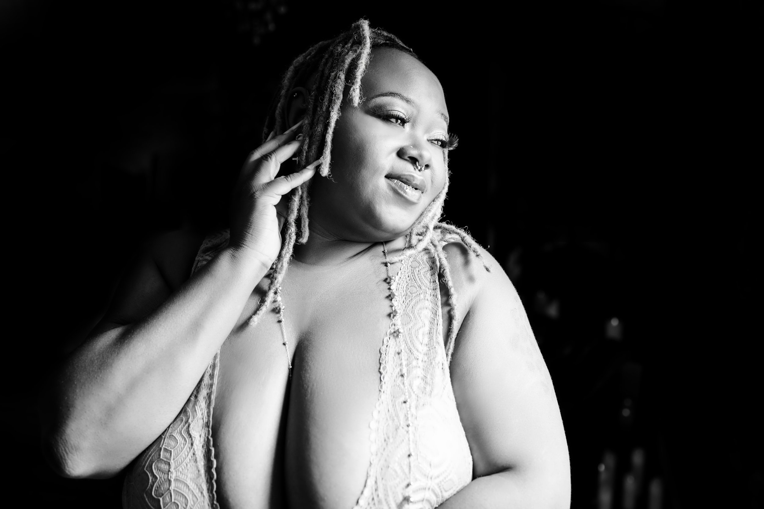 Woman with dreadlocks wearing lace lingerie in natural window light during boudoir session