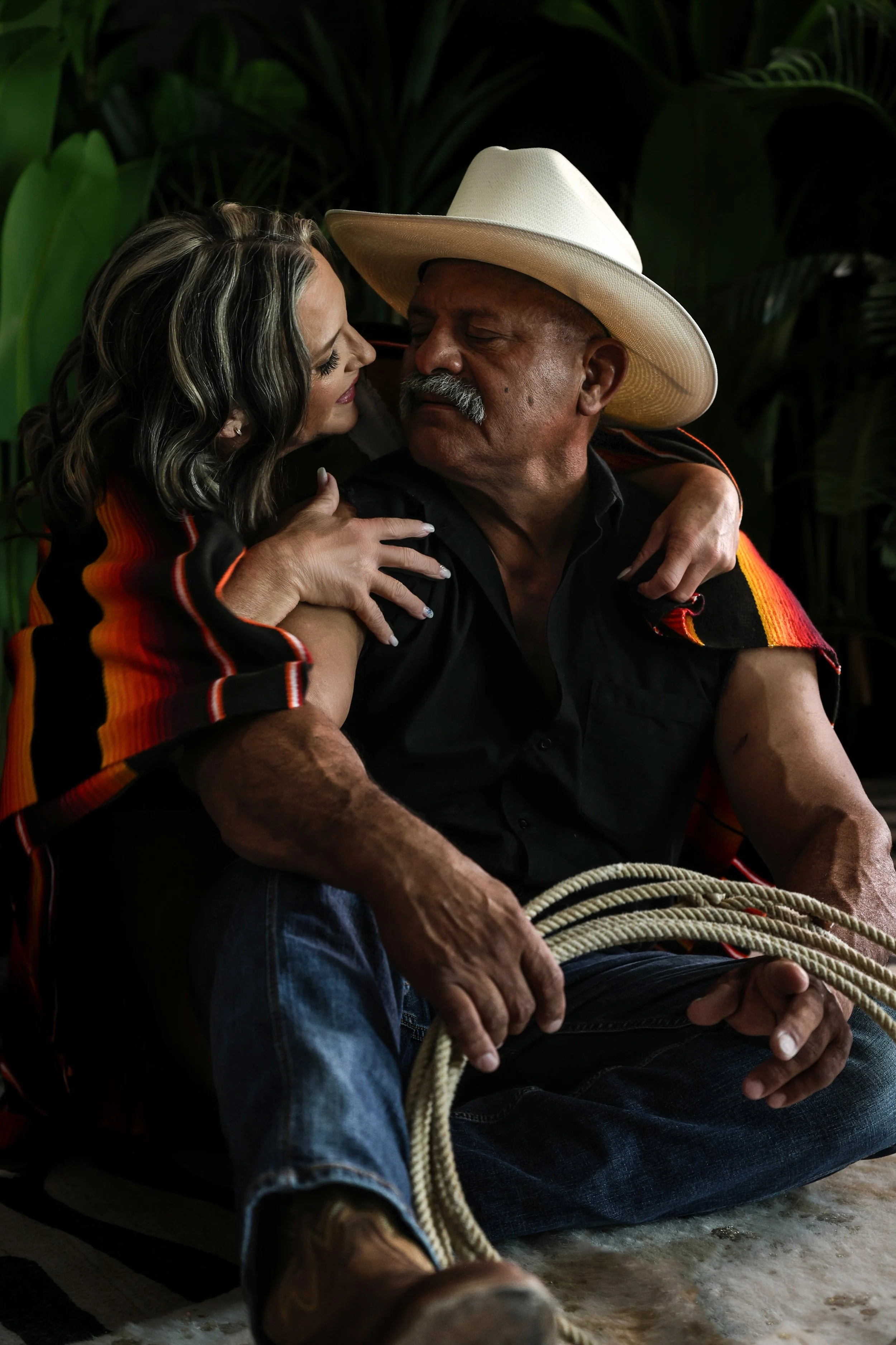 Phoenix couples boudoir photography of an older couple embracing on the floor, featuring a cowboy hat and vibrant Mexican serape blanket