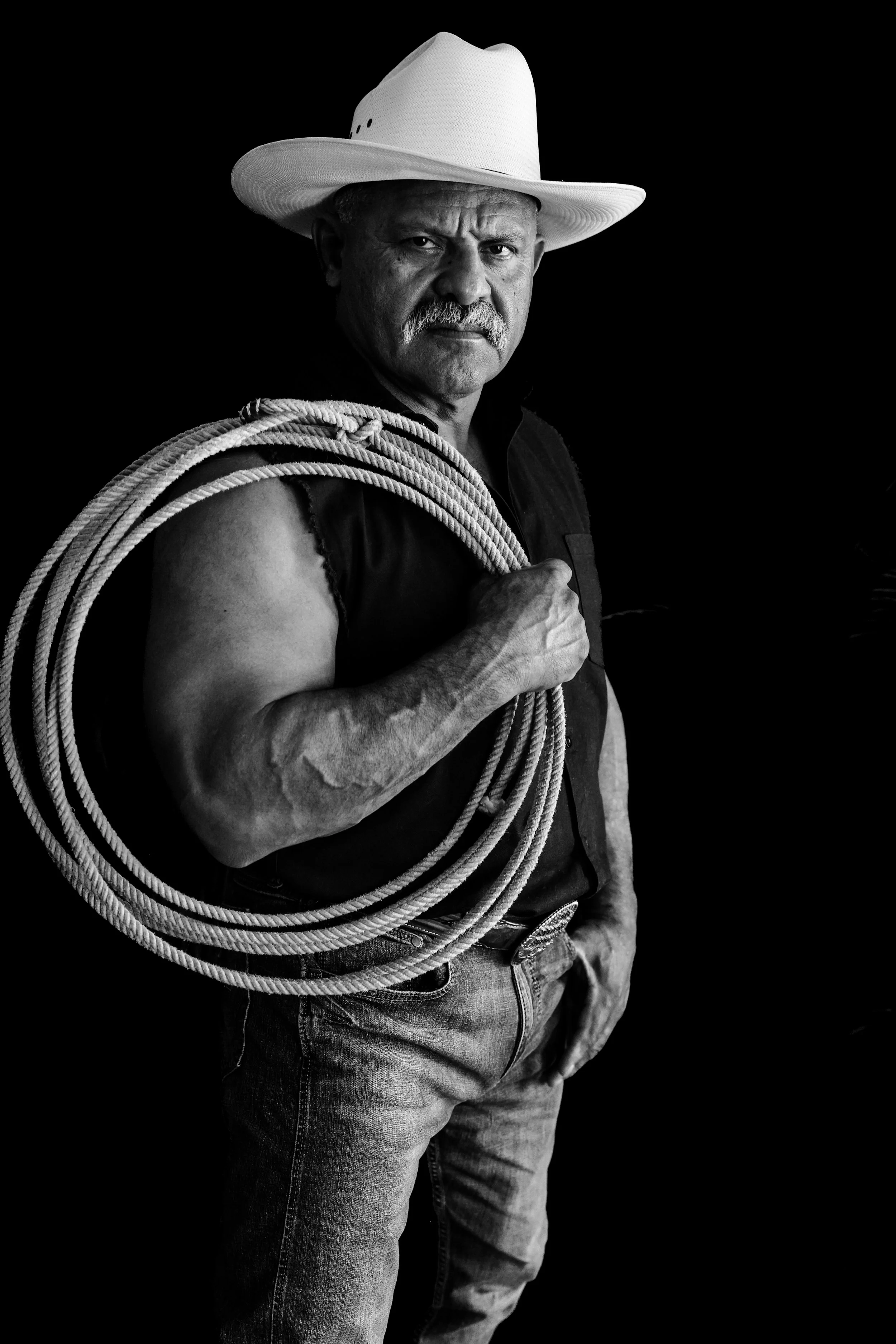 Phoenix male boudoir photography of an older gentleman in a vest and cowboy hat holding a rope, black and white portrait
