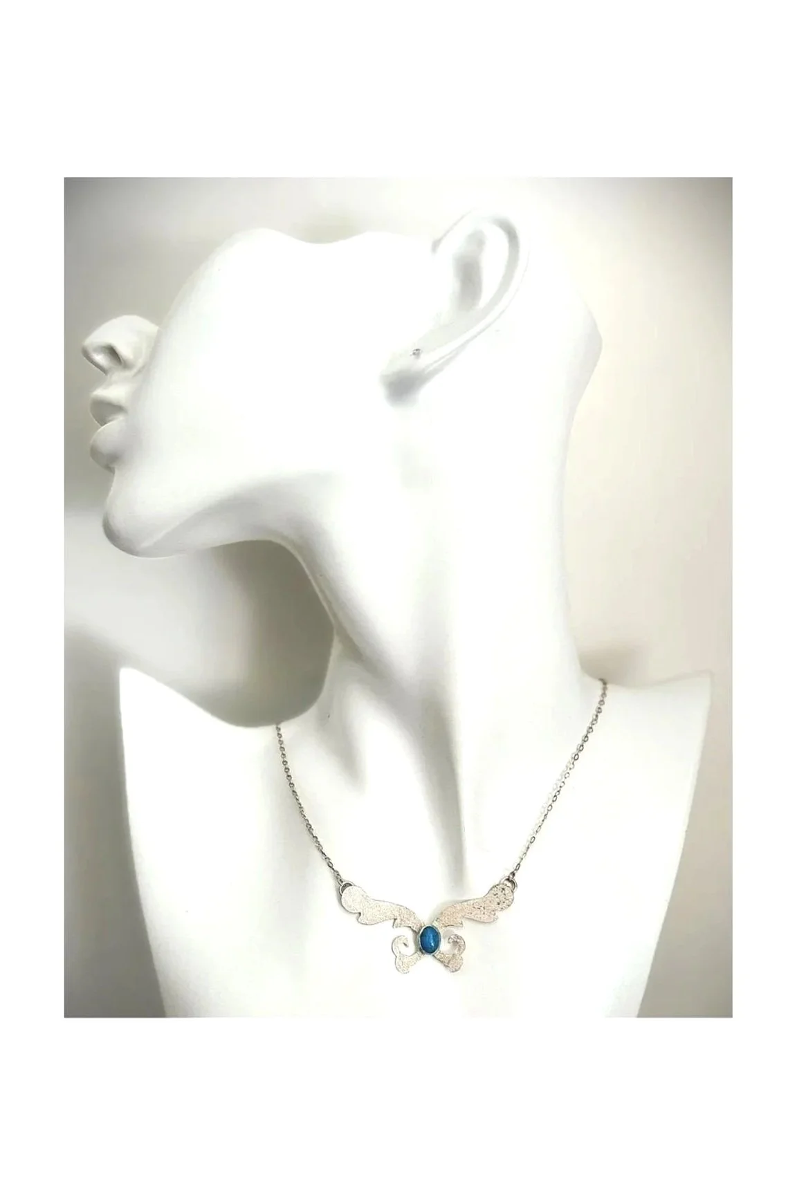 Sterling silver necklace featuring a wing-shaped pendant with an oval gemstone in the center, displayed on a white mannequin bust.