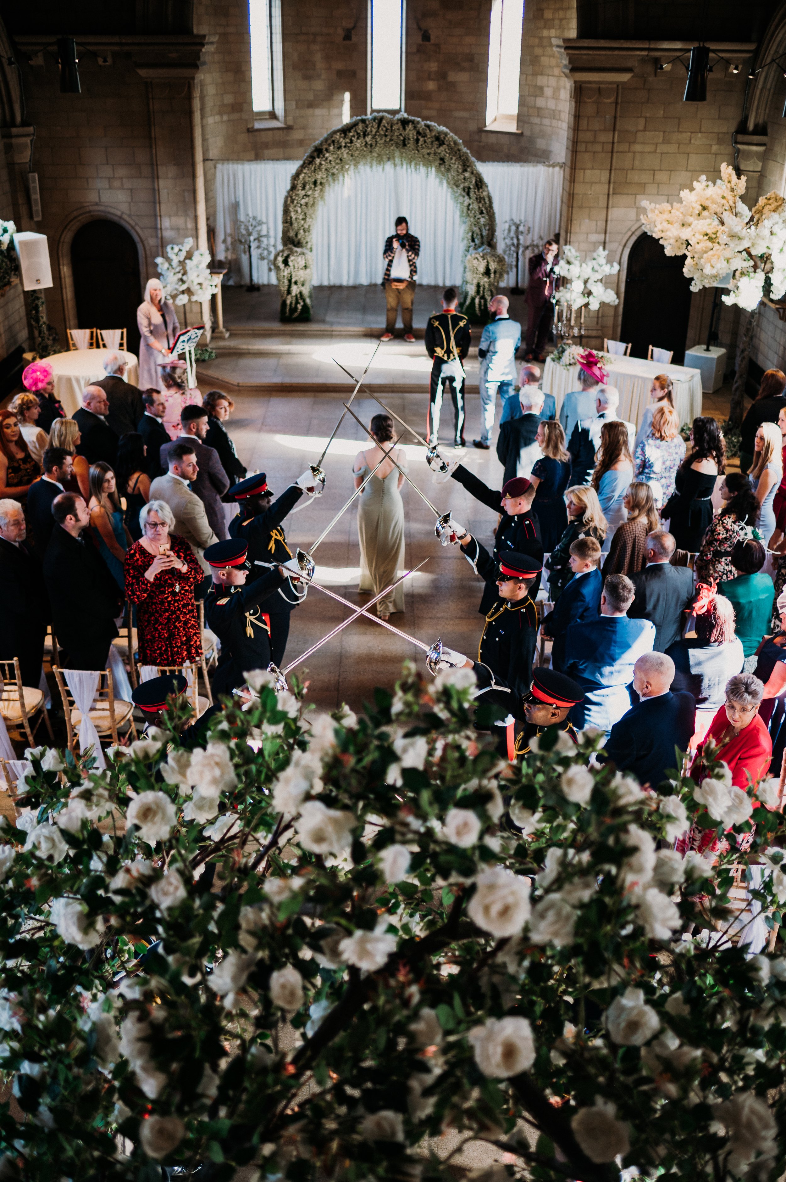 A bridesmaid walks into the ceremony room through the sword guard at Sneaton Castle, Whitby.