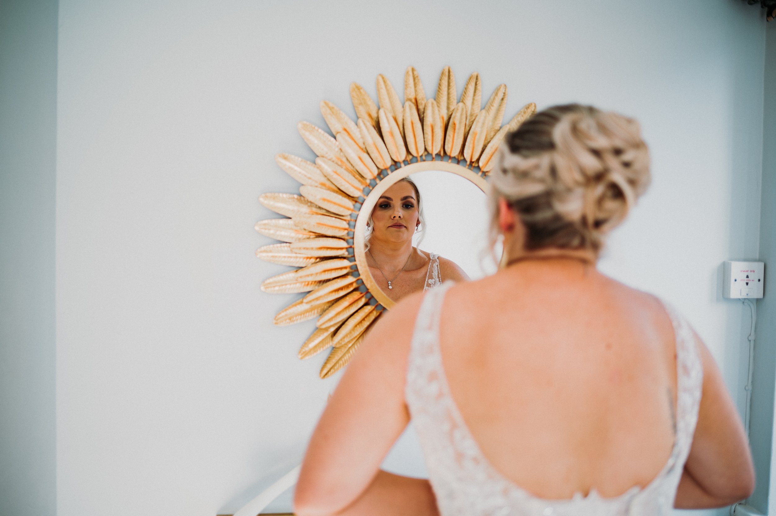 The bride checks her reflection in a gold mirror at Sneaton Castle, Whitby.