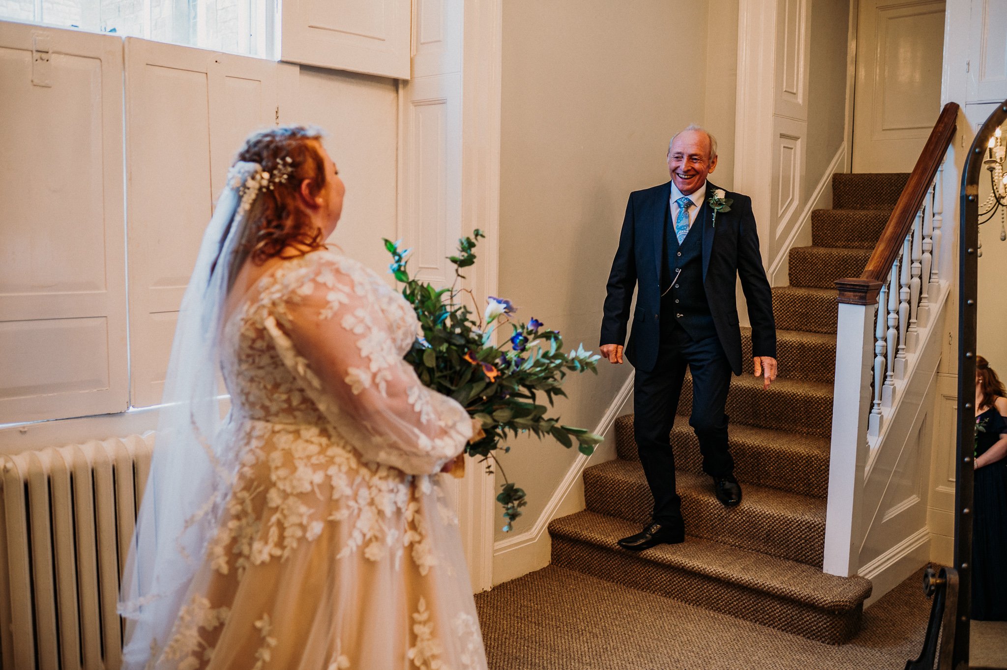 The father of the bride comes down the steps to greet his daughter in her wedding dress at Sneaton Castle, Whitby.